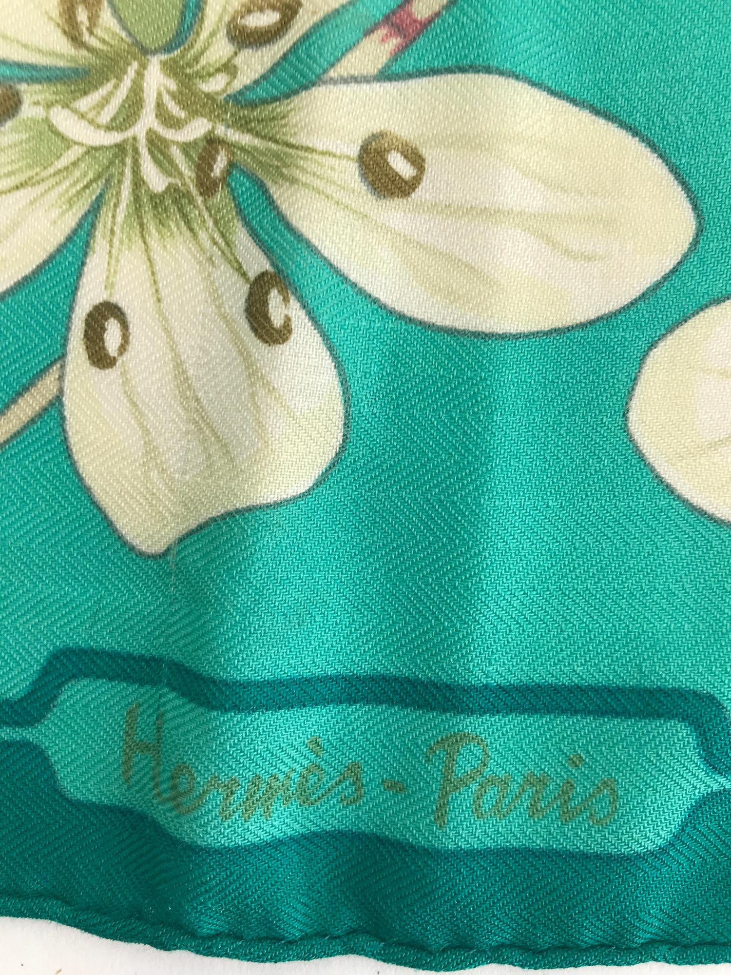 Hermes Flora Graeca cashmere twill scarf designed by Niki Goulandris 90cm. A beautiful scarf in shades of turquoise with with a center of fantasy flowers twining on vines. There is a pull, see photo of Hermes signature and two very tiny pulls along