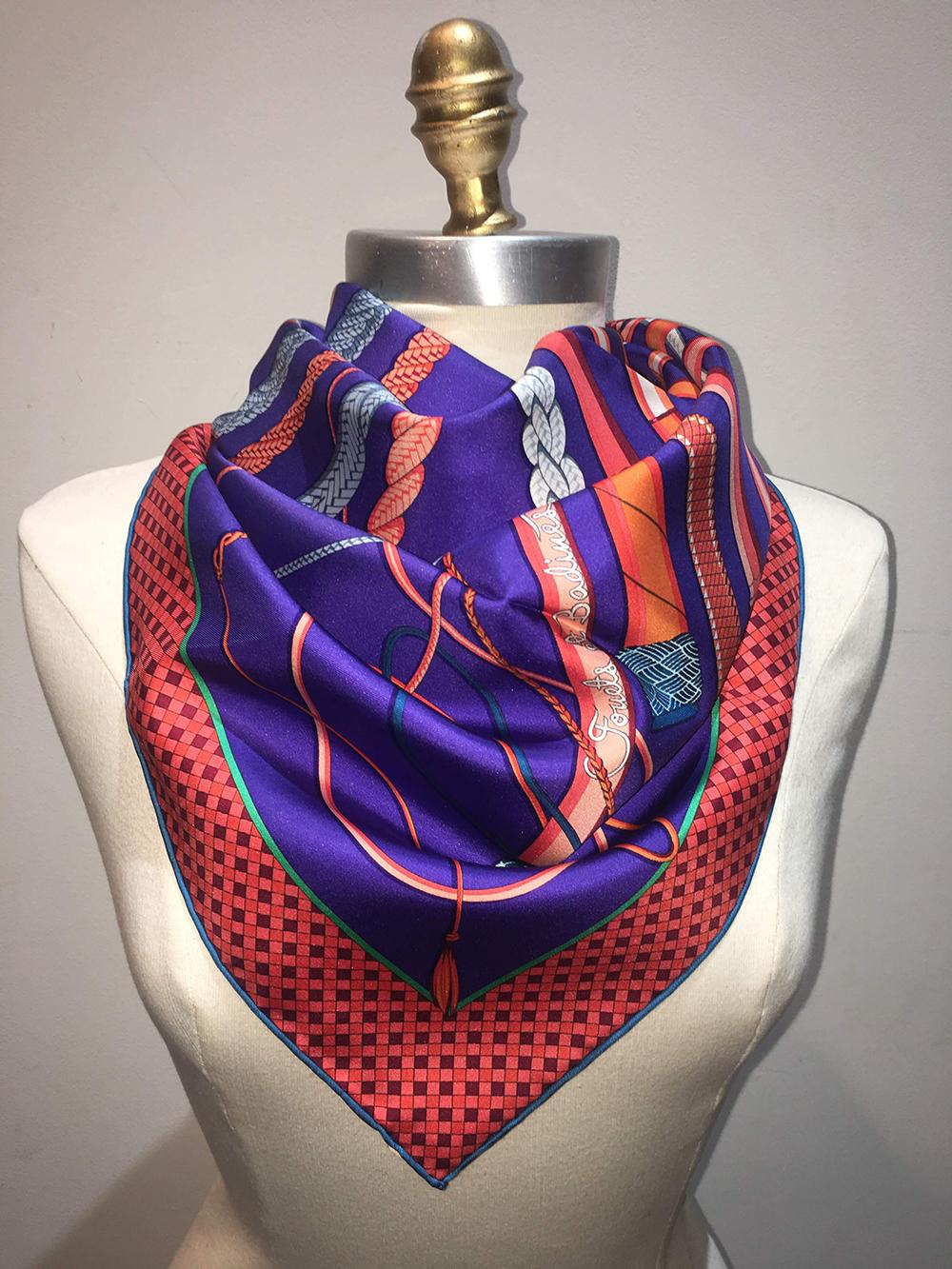 Hermes Fouets et Badines Silk Scarf in Orange and Purple in excellent like new condition. Original silk screen design c2018 by Virginie Jamin features a vibrant print of 14 different leather whips in oranges and blues over a royal purple background