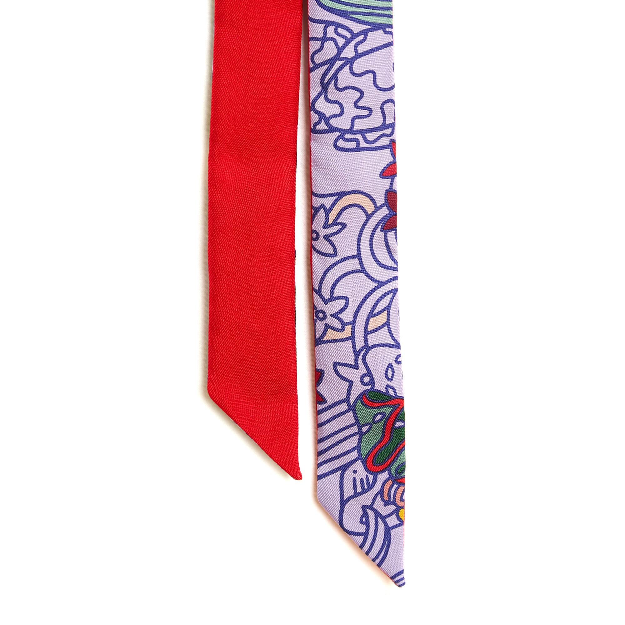 Hermès maxi Twilly or Twillon 193 scarf in double-sided silk twill, bright red on one side and purple and multi-colored on the other. Width 3 cm, length 193 cm. The scarf is in excellent condition.