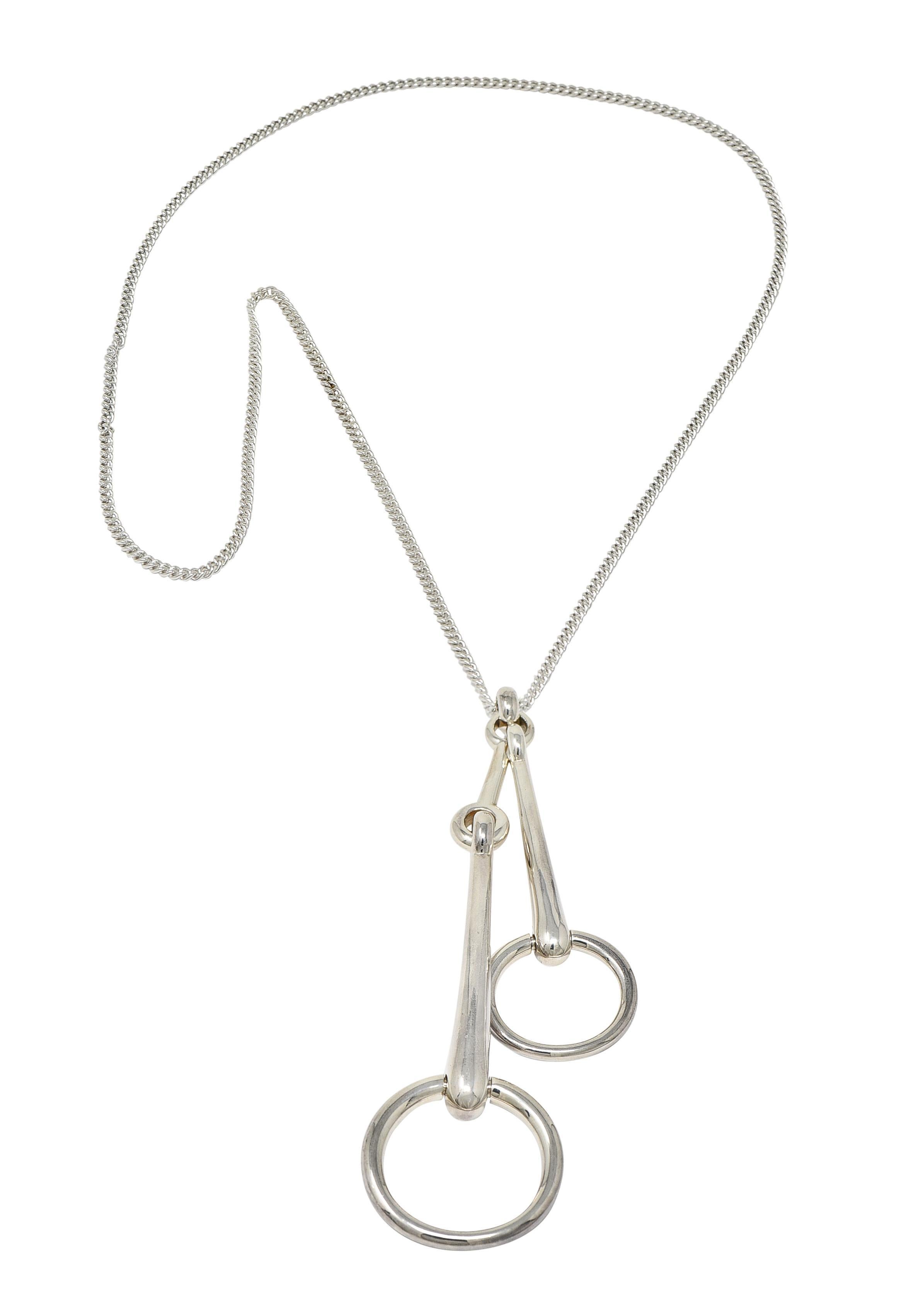 Designed as a closed curb link chain suspending a substantial horsebit pendant
Designed as one small bit and one large bit connected via bit bar
With hinged rings and looped bale
Completed by high polish finish
Stamped for sterling silver
Numbered