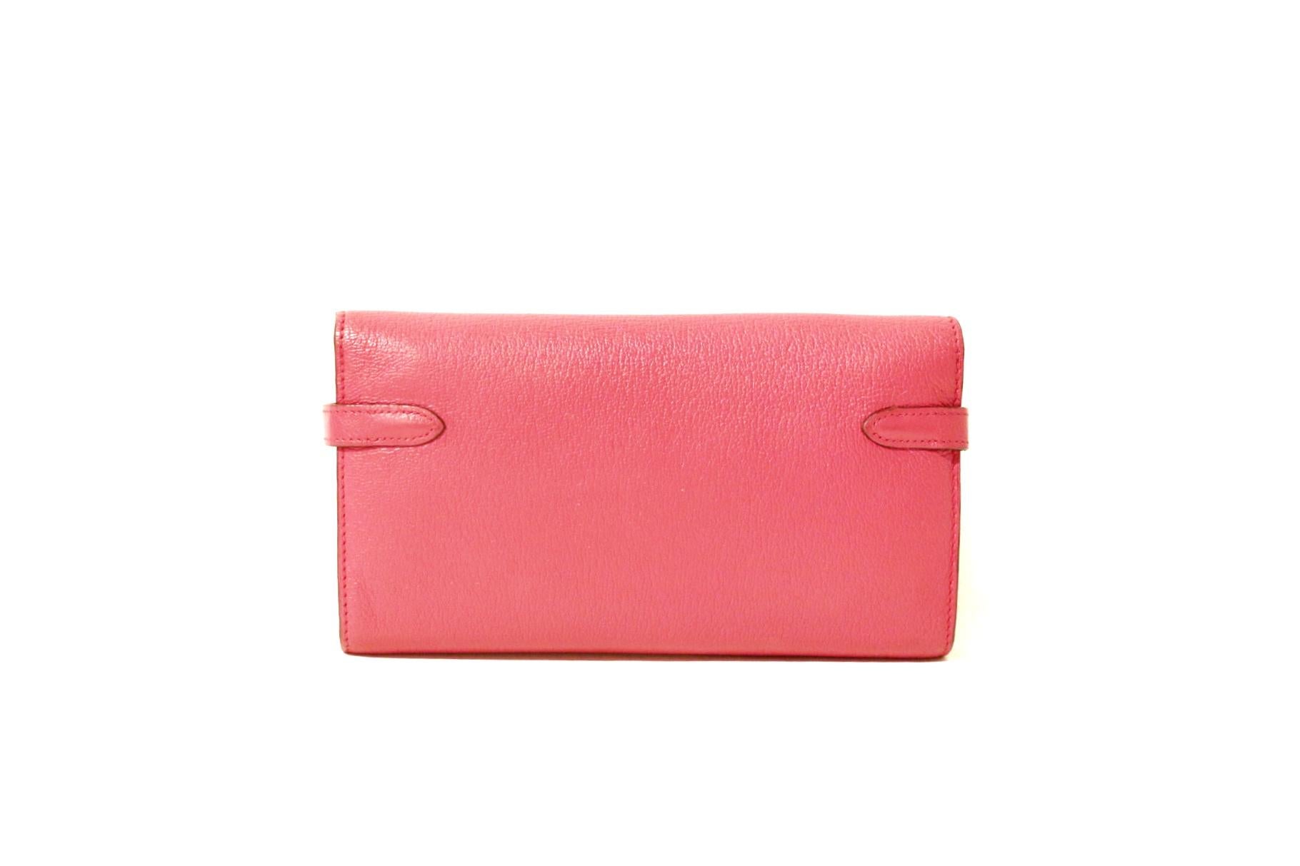 This authentic Hermès Fuchsia Chevre Kelly Wallet is in very good condition.  A beautiful pop of color in durable chevre (goat skin) leather that easily organizes coinage and currency; a brilliant find. 
Chevre is lightweight and scratch resistant,