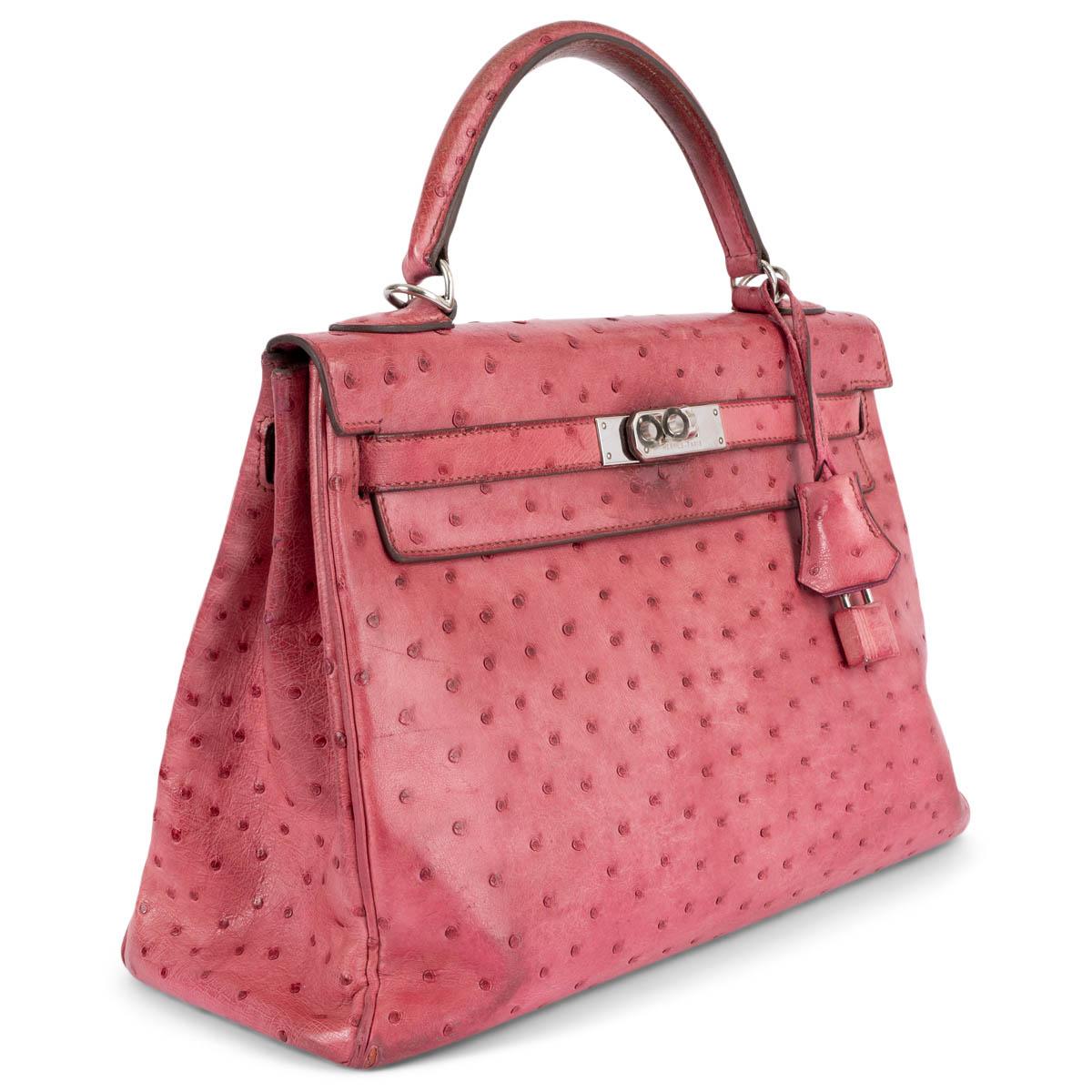 100% authentic Hermès Kelly 32 Retourne bag in fuchsia pink Ostrich leather with palladium hardware. Lined in fuchsia goat skin leather with two open pockets against the front and a zipper pocket against the back. Has been carried often and shows