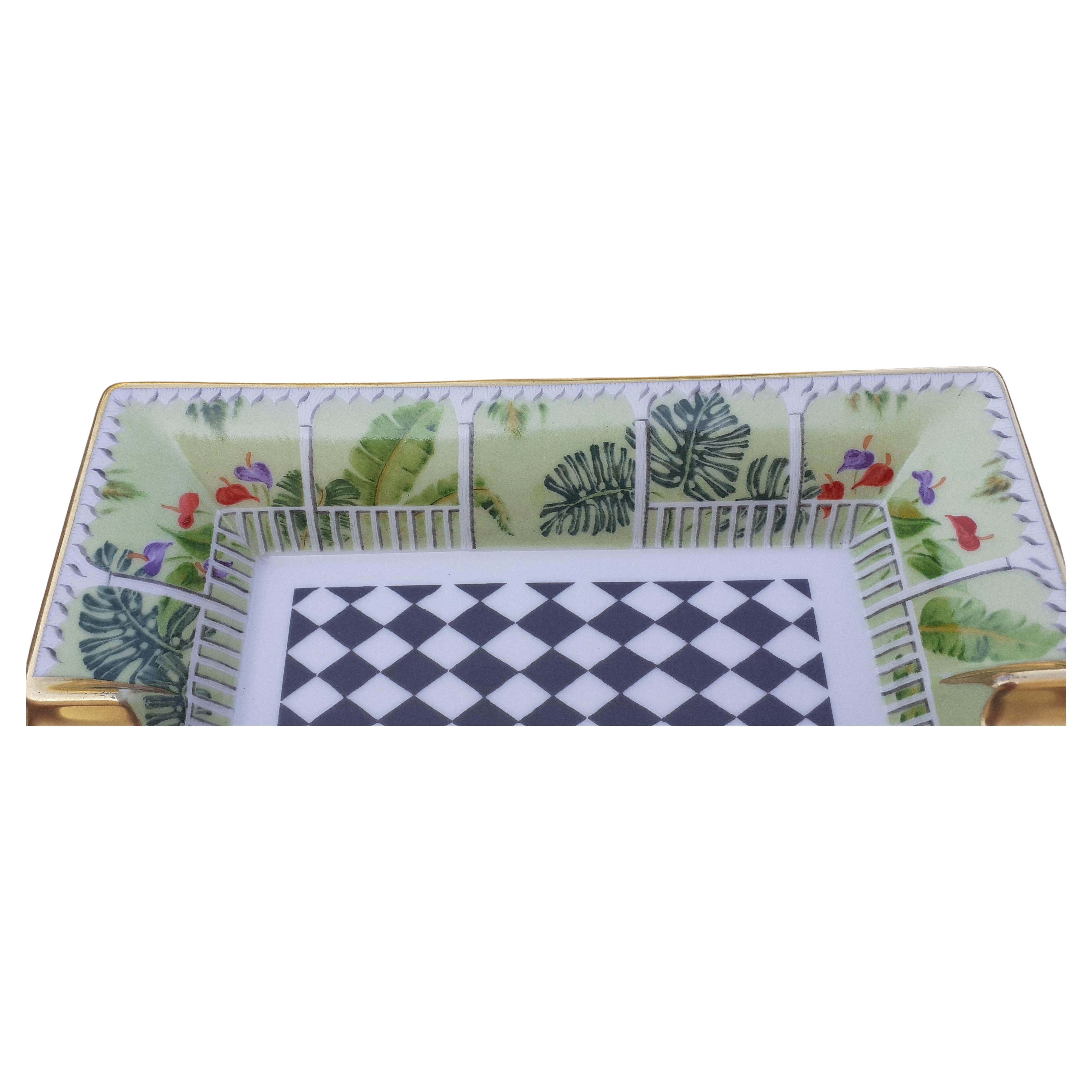 Gorgeous and Rare Authentic Hermès Ashtray

Print: the center represents a black and white checkered floor, the whole drawing a balcony with beams and lush vegetation of large foliage and aromas

Made in France

Made of porcelain, edges and notches