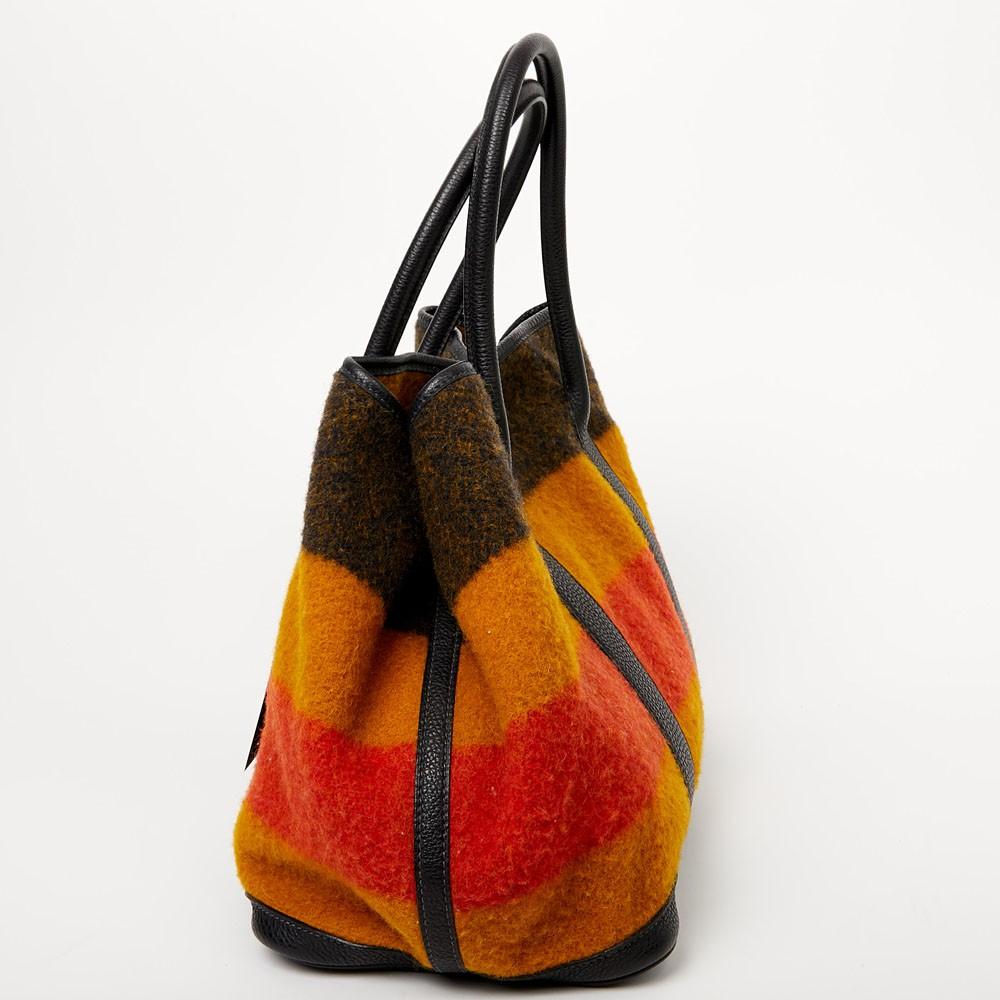 Sobria, sportiva e rilassata, la Garden Party è la tote bag per eccellenza. Sui lati, 3 bottoni automatici in argento palladio regolano l'apertura e offrono un'ampia capienza. Realizzate in pelle e lana, il colore arancione dà energia e rivisita i