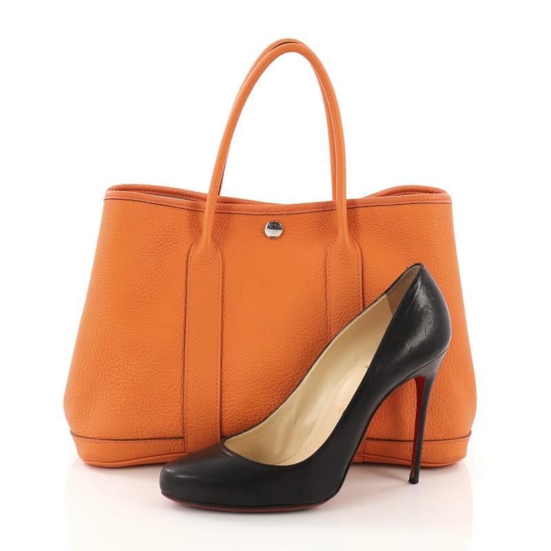 This Hermes Garden Party Tote Leather 30, crafted from Orange H negonda leather, features dual rolled leather top handles, side snap buttons, and palladium-tone hardware. Its button closure opens to a beige fabric interior with zip pocket. Date
