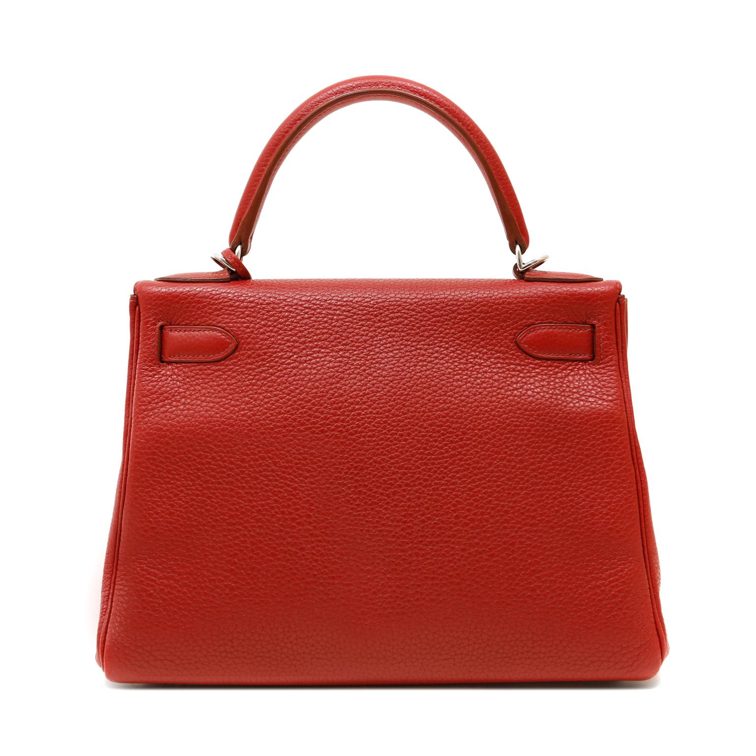 This authentic Hermès Garnet Red Togo Leather 28 cm Kelly is in excellent condition.  The ladylike Kelly is in high demand and requires extensive waiting periods from Hermès.  Deep lipstick red paired with Palladium hardware is a stunning and