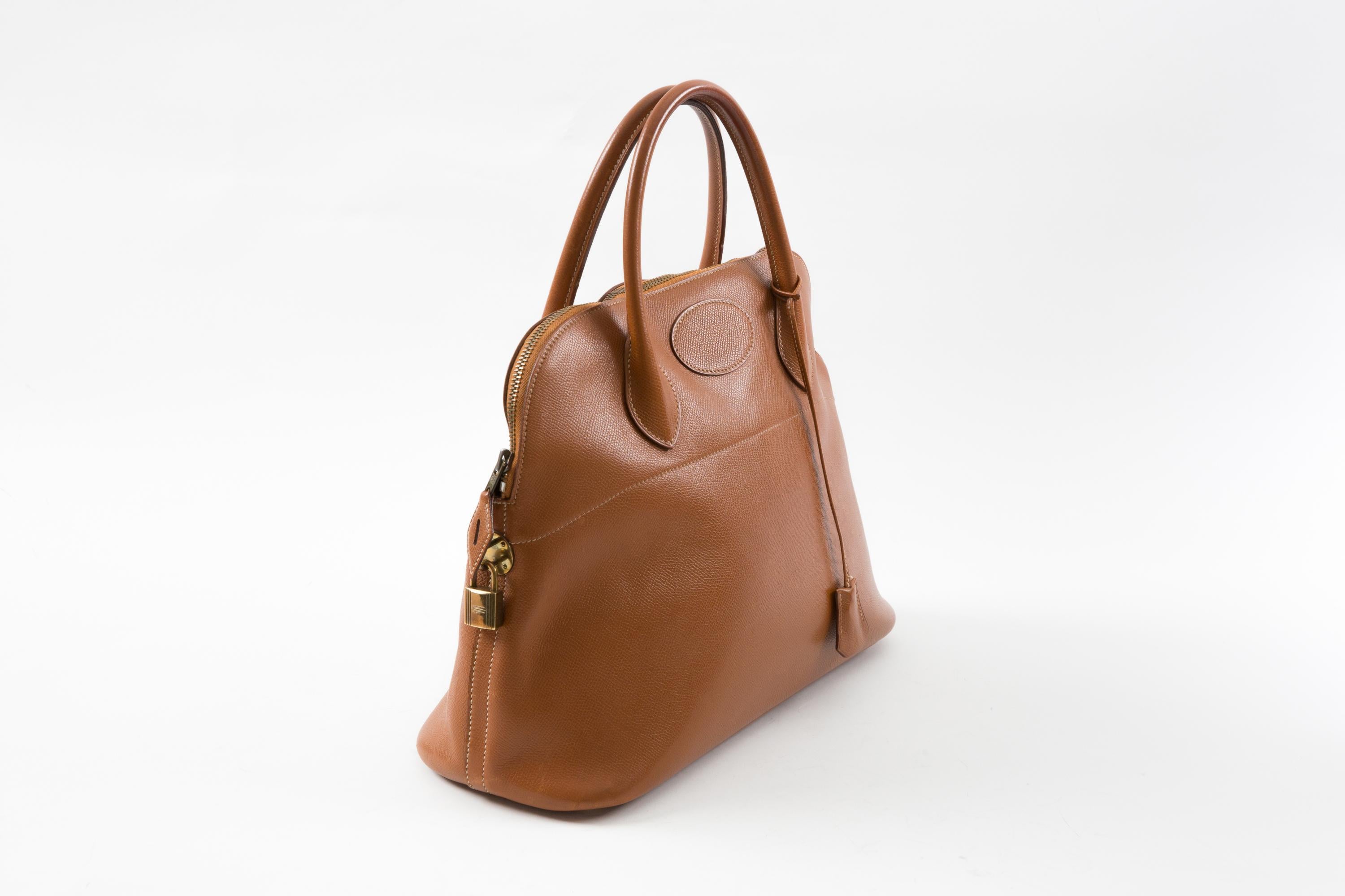 Hermes Gold “Bolide 35” Courchevel leather handbag  featuring gold plated hardware with top zipper closure. Circa 1990 stamped T circle, leather lining with inner slip pocket, set keys, clochette and padlock. Circa 1990. 
Circa 1990 (T circle)
In