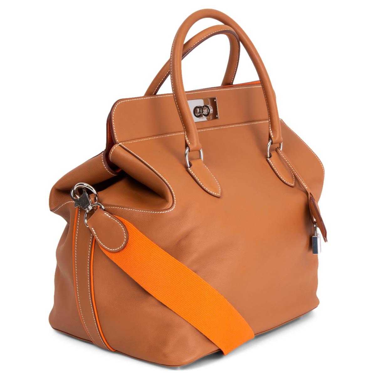 100% authentic Hermès Toolbox 33 Verso bag in Gold (camel) smooth Swift calfskin. The bag features rolled leather top handles with palladium metal links, an optional orange canvas shoulder strap with palladium clasps, and palladium metal frontal
