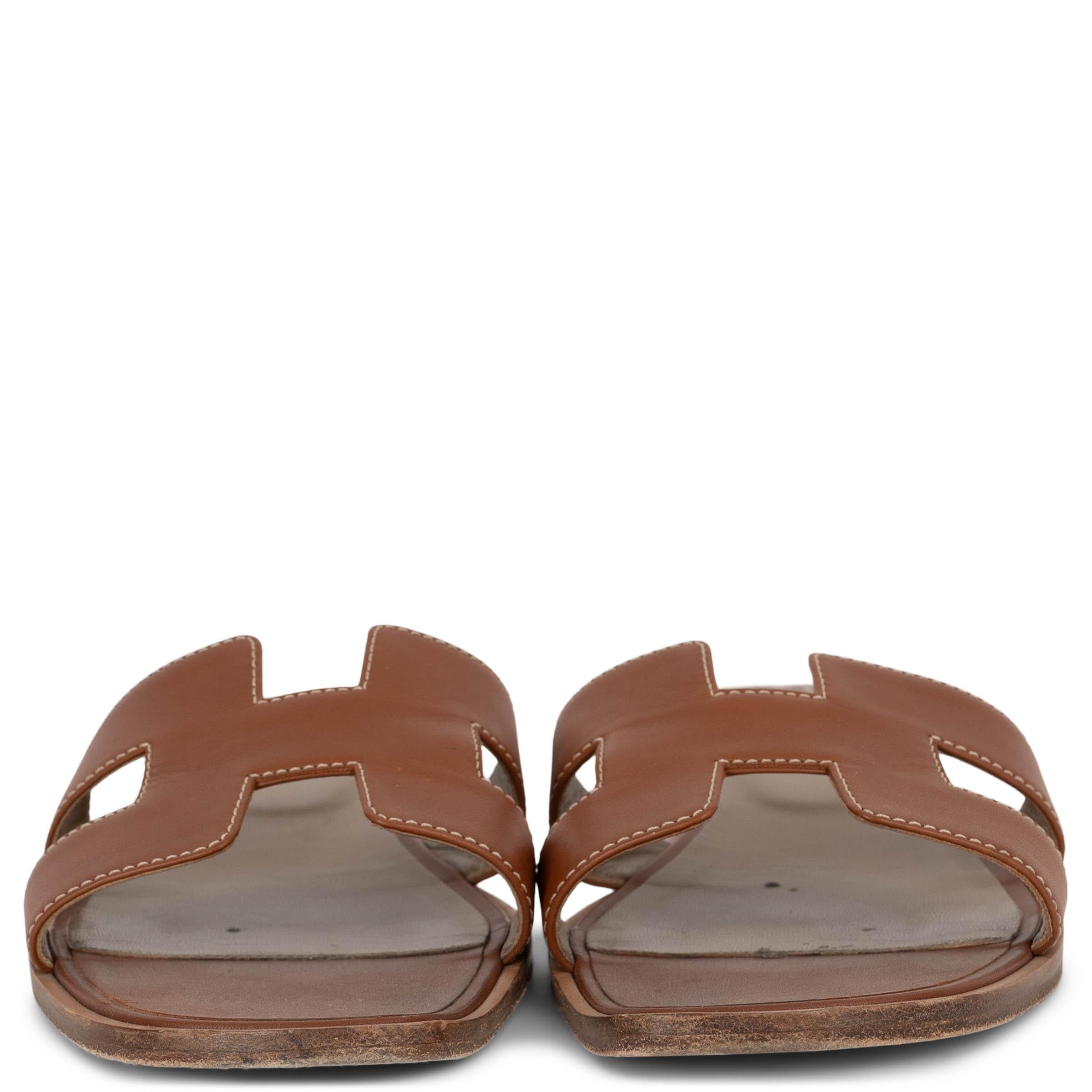 Diese 100% authentischen Hermès Oran Slide-Sandalen in Gold (camel) Box aus Kalbsleder verkörpern zeitlose Eleganz und mühelosen Stil. Diese eleganten Pantoletten mit dem kultigen H-Ausschnitt sind ein Beweis für die unverwechselbare Handwerkskunst