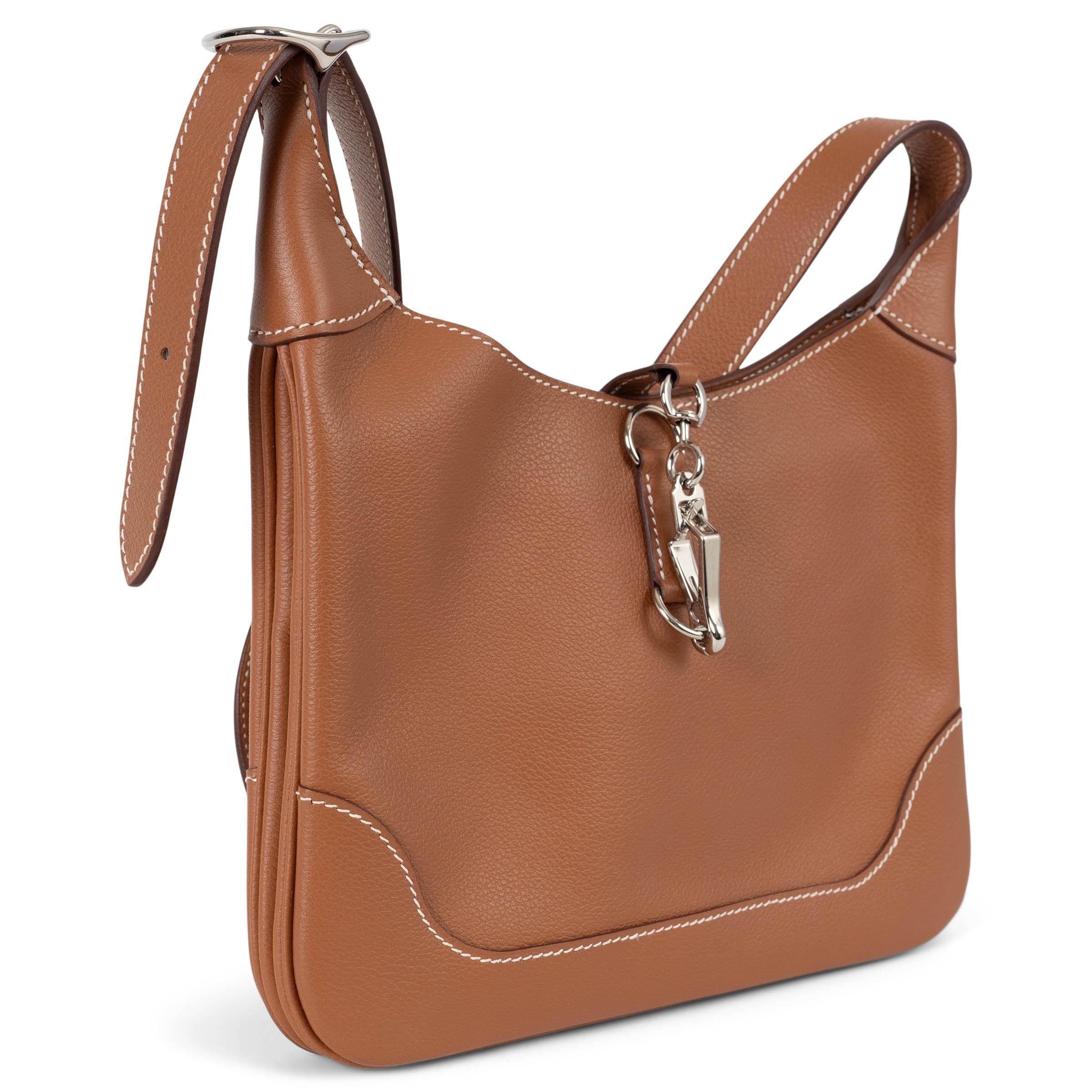 Diese 100% authentische Hermès Trim Duo 24 Umhängetasche aus Gold (camel) Veau Evercolor Leder steht für raffinierte Eleganz im Alltag. Sie ist mit kontrastierenden weißen Nähten und Palladium-Hardware ausgestattet und verfügt über einen