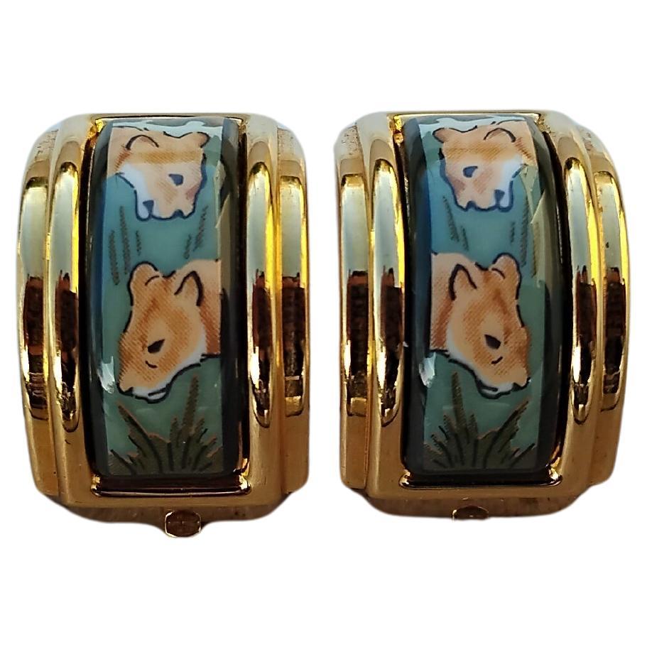 Superbes et rares boucles d'oreilles Hermès authentiques

Imprimer : Lionnes

Fabriqué en émail imprimé et quincaillerie plaquée or jaune

Coloris : Beige, nuances de vert

