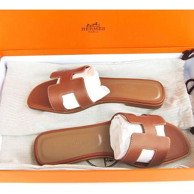Hermes Gold Tan Oran Sandals 39 or 8.5 Shoes Iconic Classic New 2021 
Just purchased from Hermes store in 2021.
Brand New in Box.  Store fresh. Pristine condition.
Perfect and classic gift!  Comes with Hermes sleepers and orange Hermes box.
The