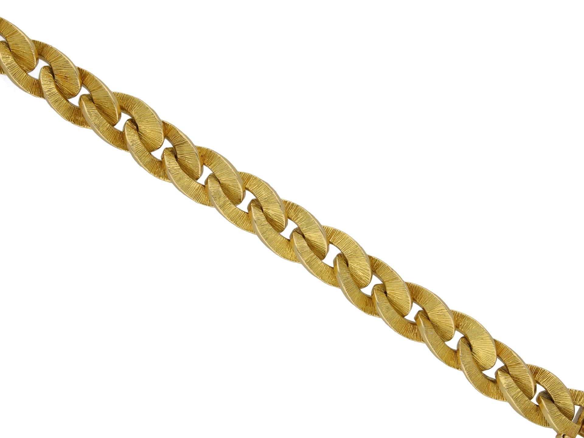 Hermes gold textured bracelet. A yellow gold articulated bracelet comprised of a flat oval curb link chain with linear textured detailing, polished edges and fitted with a secure integrated push clasp with safety catch, approximately 8