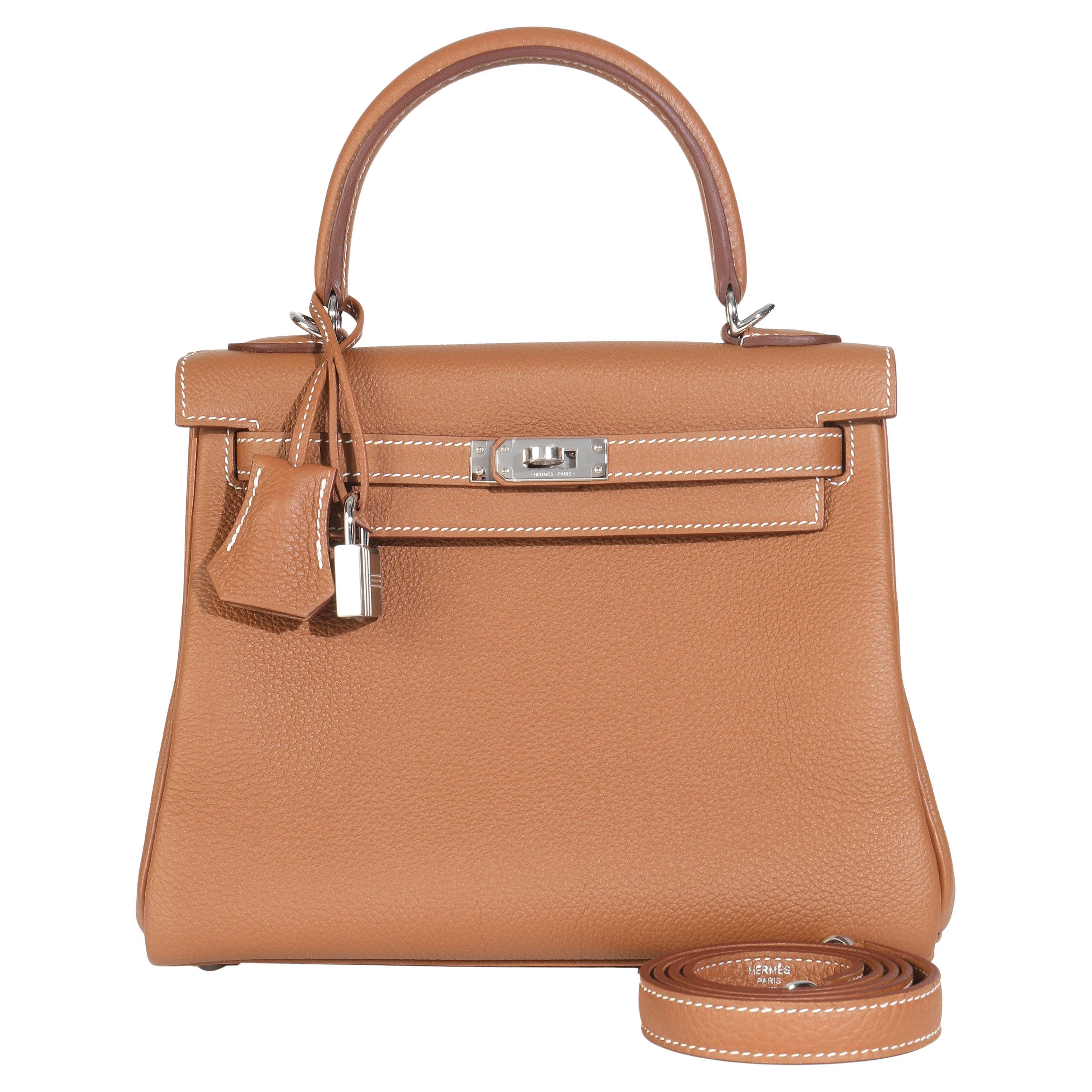 Hermès Oro Togo Retourne Kelly 25 PHW
SKU: M148068

Condit Description: Rinominata ufficialmente nel 1977, la tote bag Kelly di Hermès si chiamava originariamente Sac à Dépêches (che si traduce come 