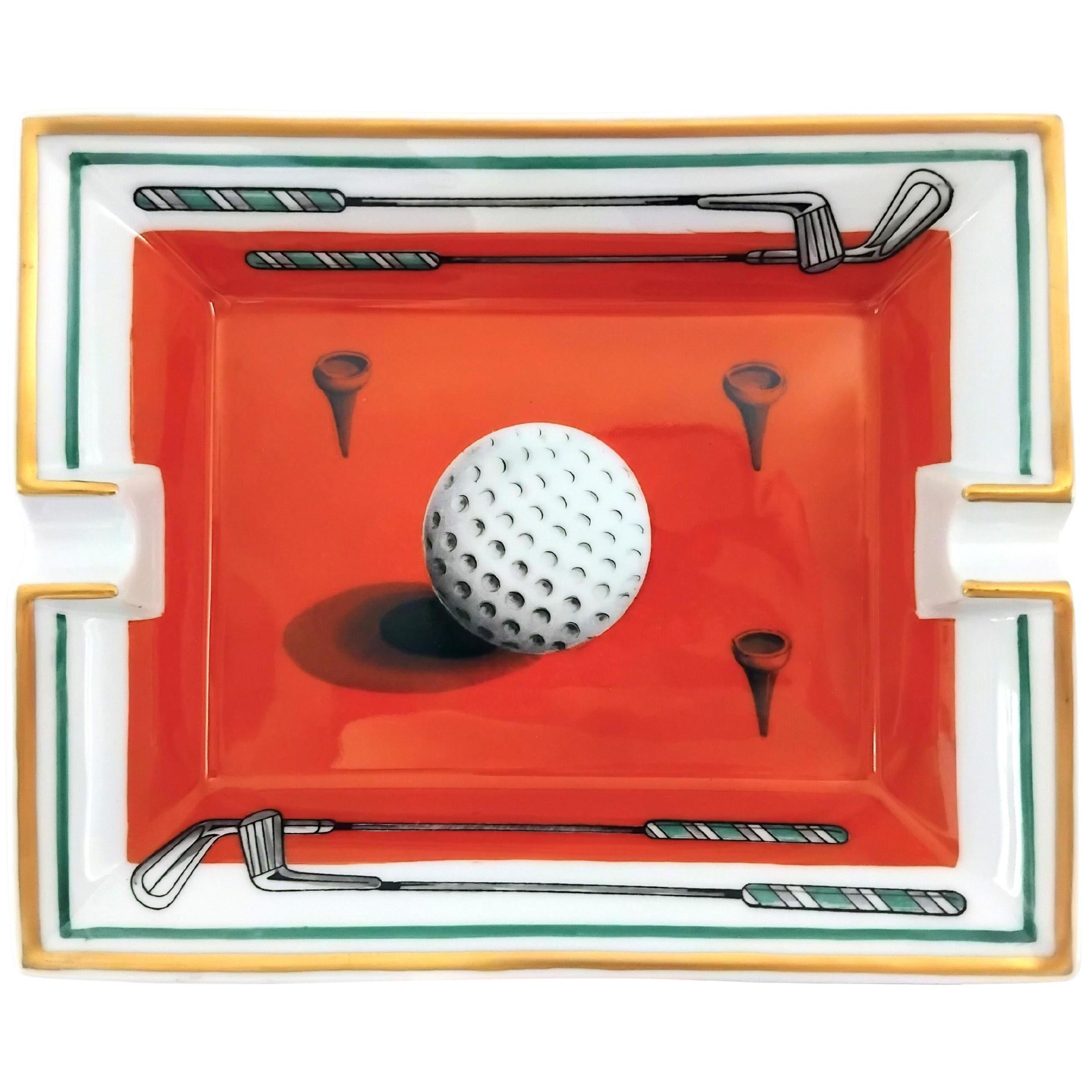 Rare and Beautiful Authentic Hermès Ashtray

Print: Golf ball, clubs and tees

Made in France

Vintage item

Made of porcelain, edges and notches hand painted with fine yellow gold

Bottom covered with beige suede leather, 