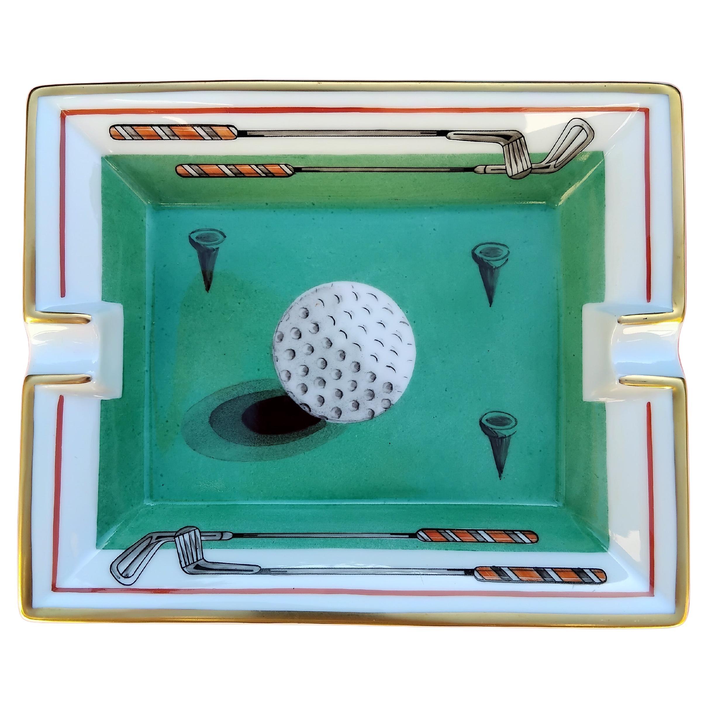 Rare and Beautiful Authentic Hermès Ashtray

Print: Golf Ball, clubs and tees

Made in France

Vintage item

Made of porcelain, edges and notches hand painted with fine gold

Bottom covered with beige suede leather, 