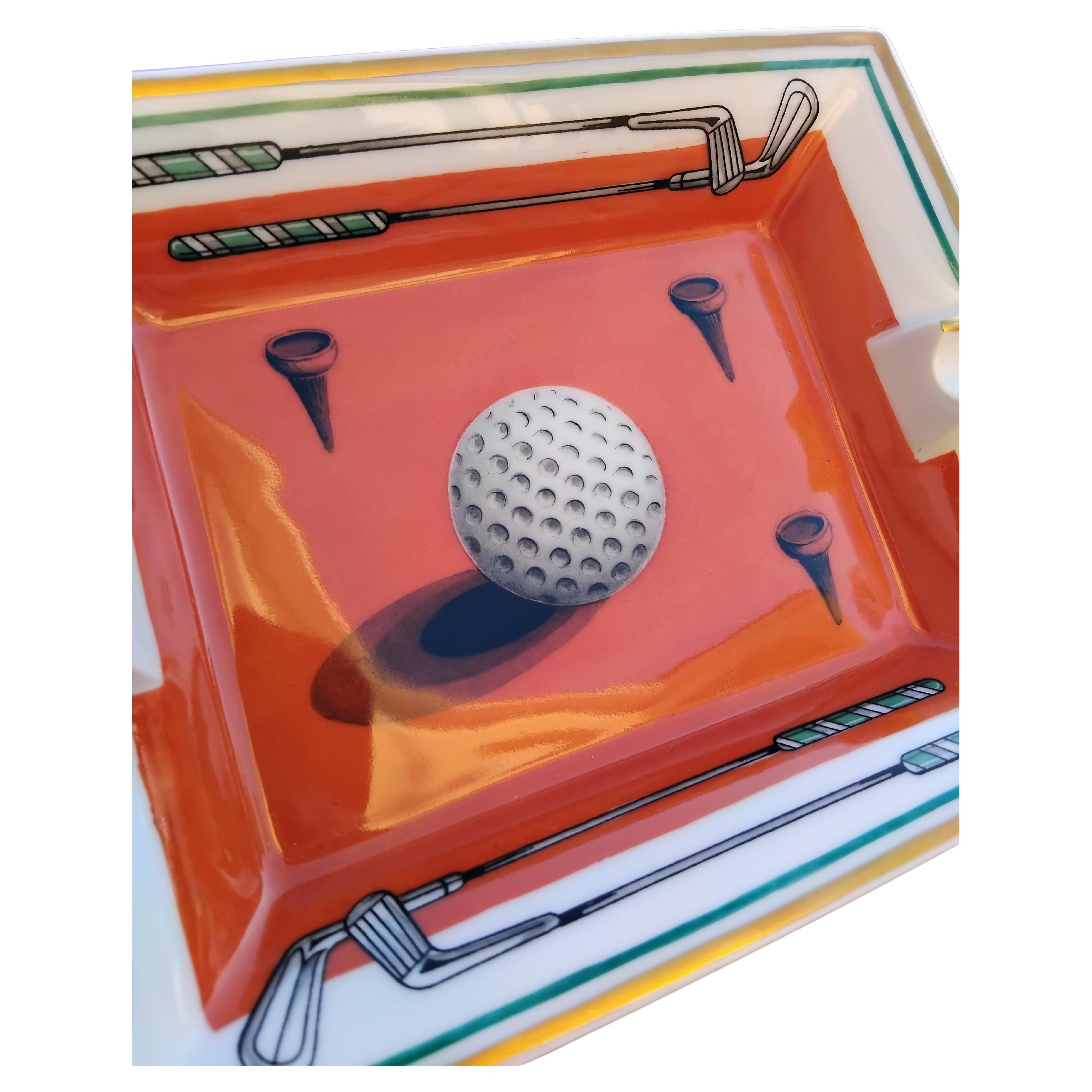 Rare and Beautiful Authentic Hermès Ashtray

Print: Golf ball, clubs and tees

Made in France

Vintage item

Made of porcelain, edges and notches hand painted with fine yellow gold

Bottom covered with grey suede leather, 