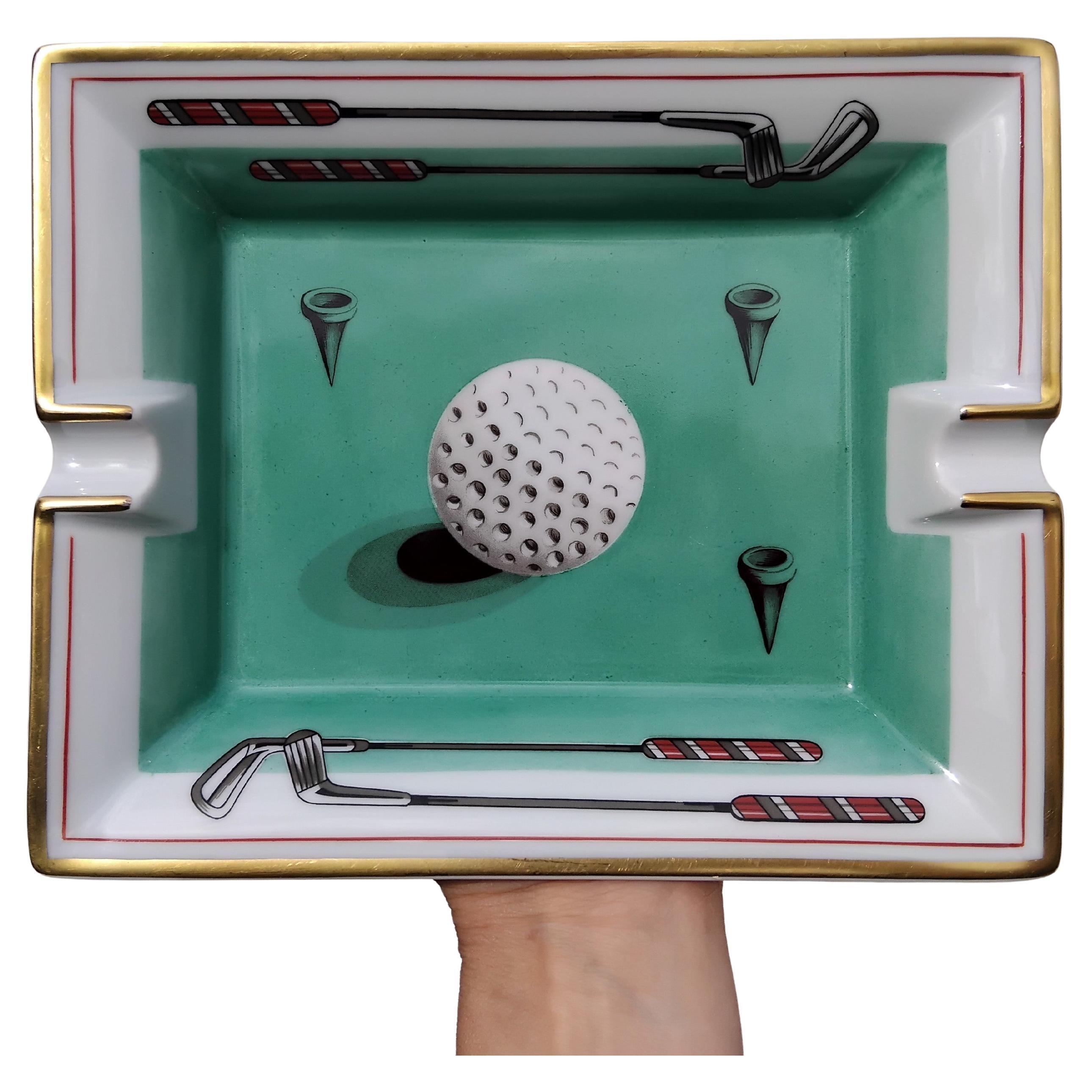 Rare and Beautiful Authentic Hermès Ashtray

Print: golf ball, clubs and tees

Made in France

Vintage item

Made of porcelain, edges and notches hand painted with fine gold

Bottom covered with green suede leather, 