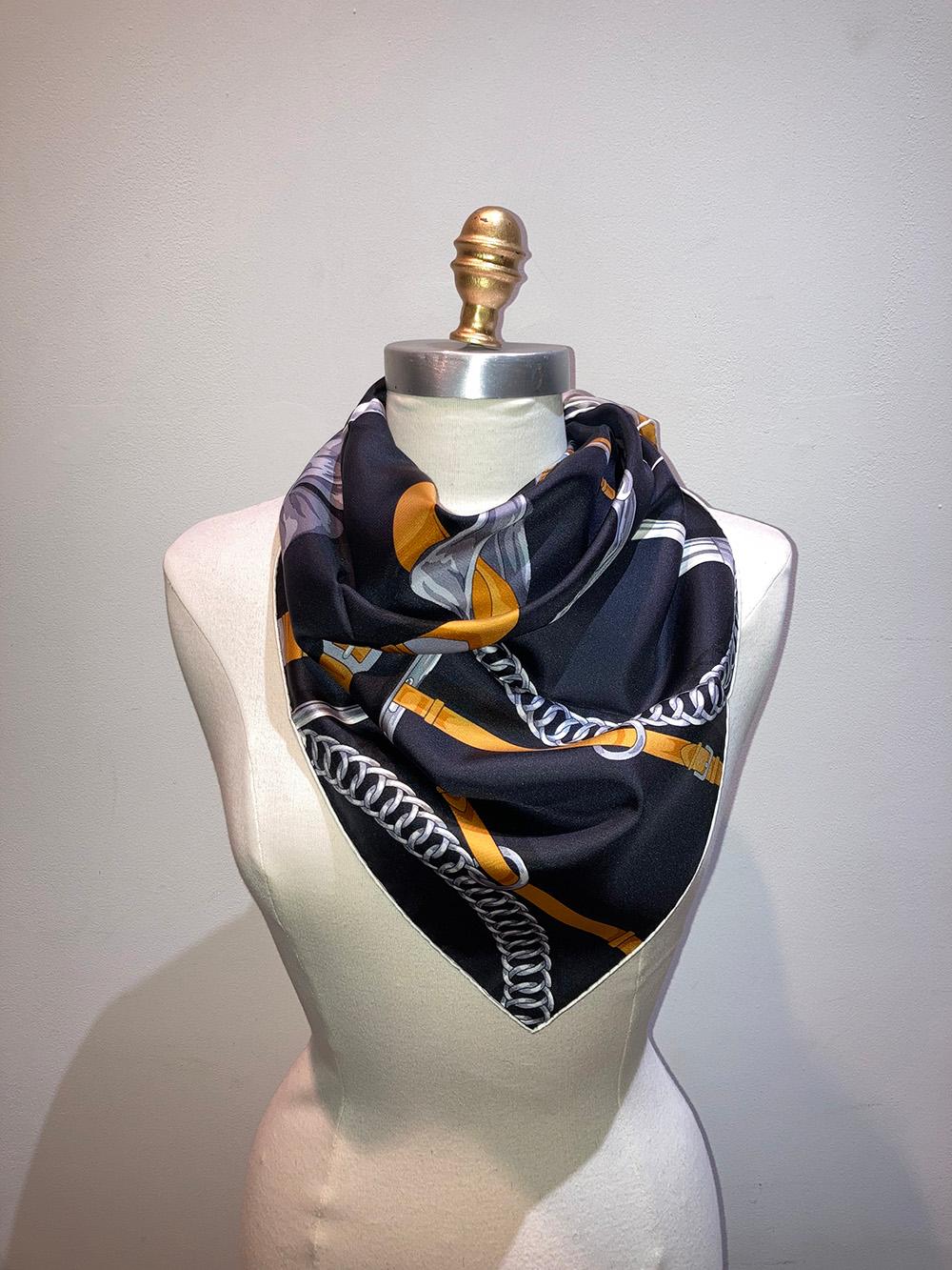 Hermes Grand Manege Detail Silk Scarf in excellent condition. Original silk screen design c2018 by Henri d'Origny features black, gold, beige, cream and grey equestrian bows, belts, buckles, bridles, and hardware print. 100% silk, hand rolled hem,