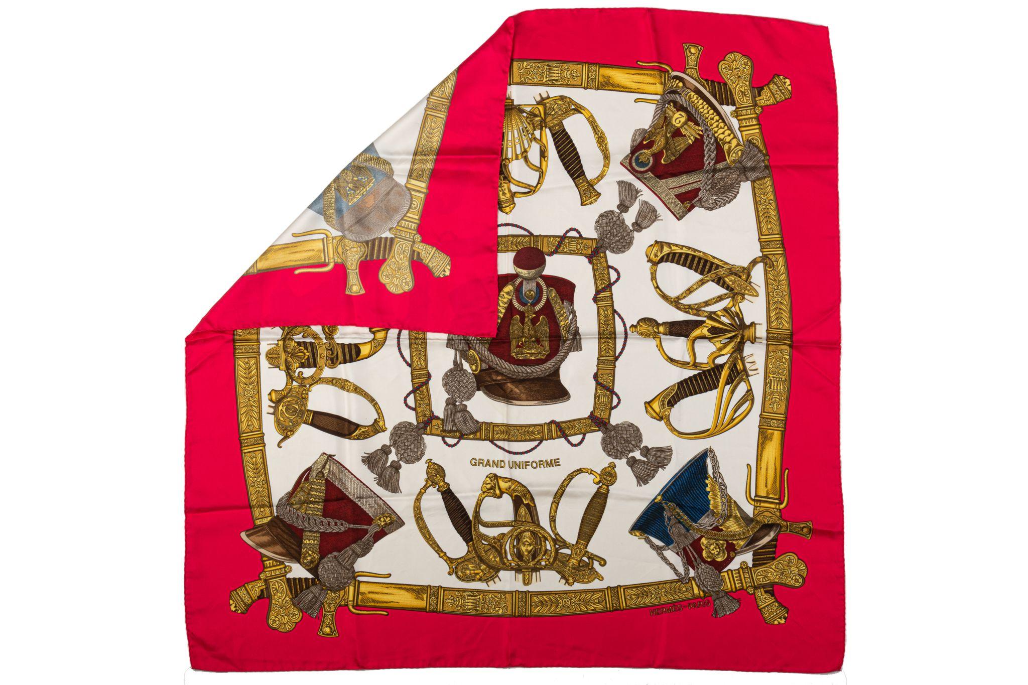 Hermès vibrant red Grand Uniforme silk twill scarf designed by coveted designer Metz. Depicts military head wear and swords. Hand-rolled edges. Does not include box. Minor wear. No care tag.