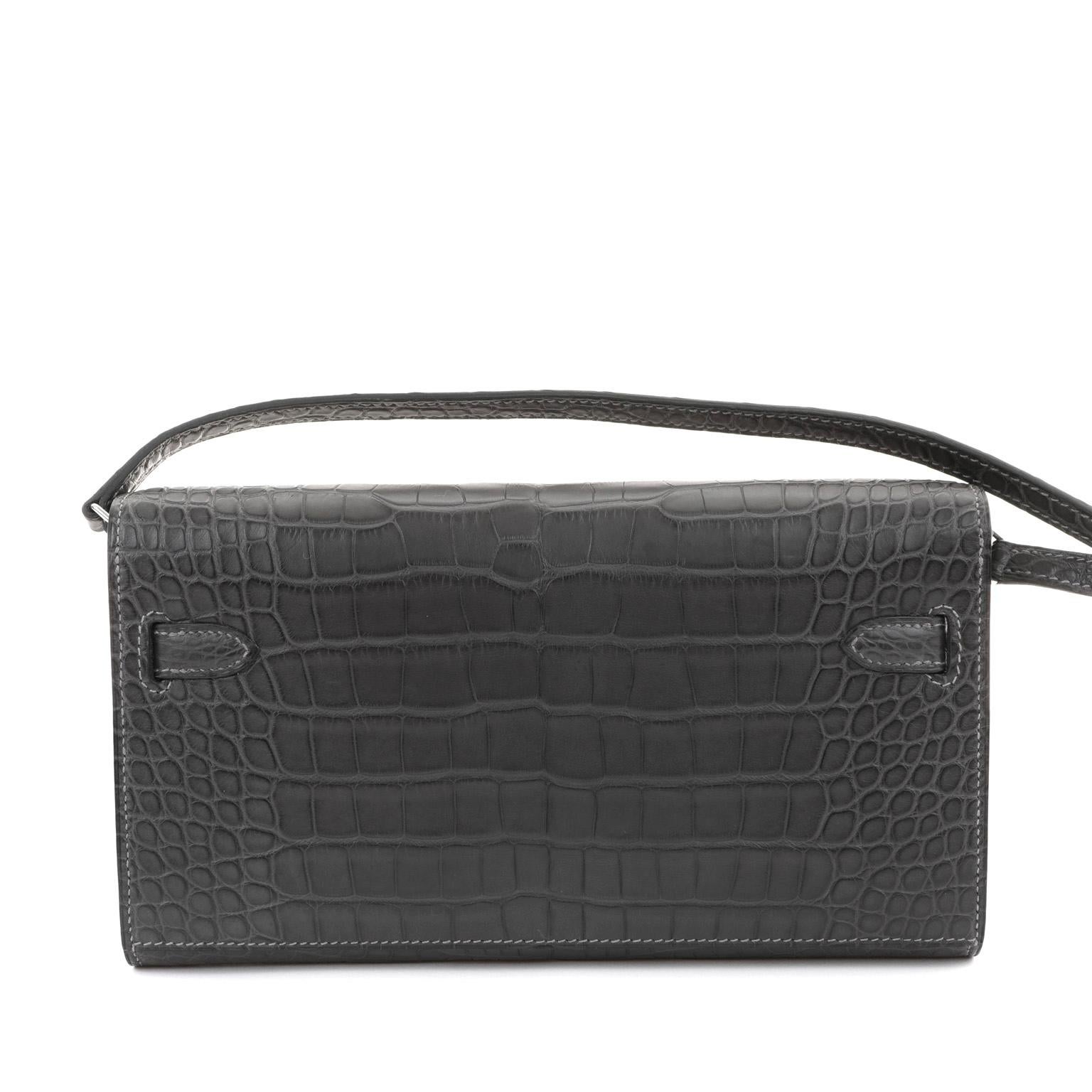 This authentic Hermès Graphite Alligator Kelly To Go Wallet is in pristine unworn condition with the protective plastic intact on the palladium hardware.  Sleek, stylish and versatile, the To Go Wallet functions a cross body bag as well as a holder