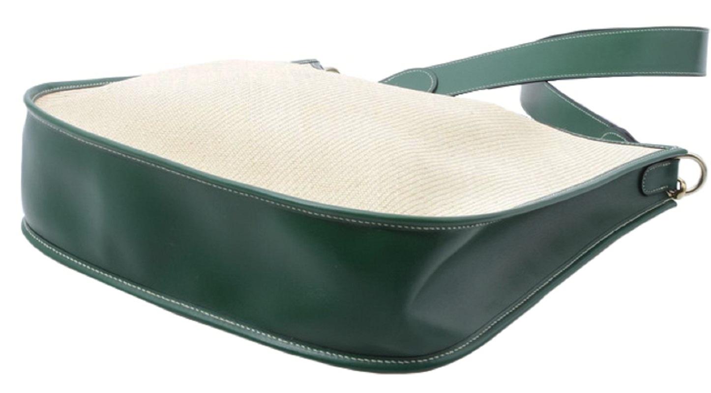 Green leather and neutral canvas Hermes Evelyne I Panama crossbody bag with gold-tone hardware, single flat shoulder strap, exterior slip pocket at back, signature perforated 'H' logo at front, green leather lining and snap closure at flap.

