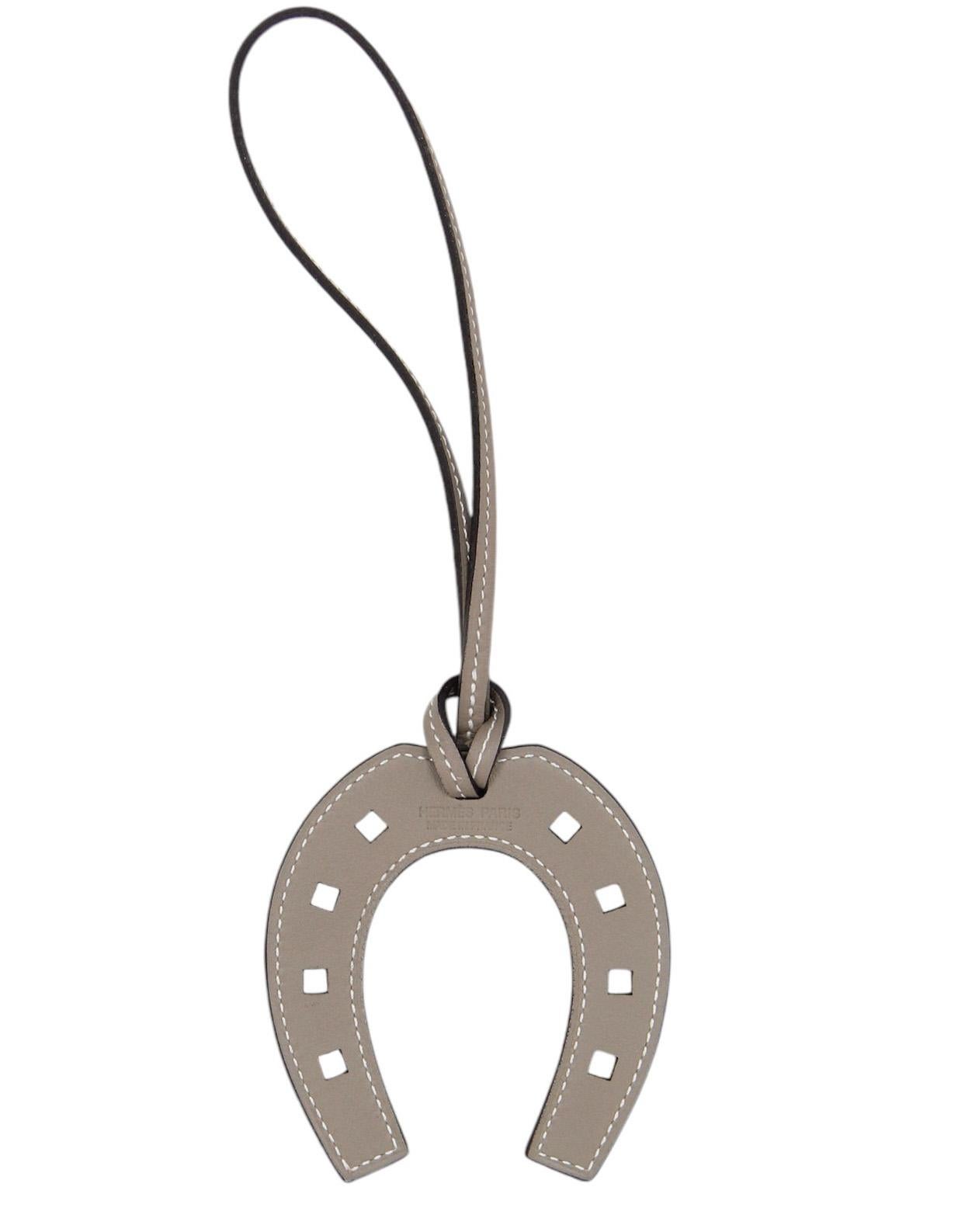 Hermes Grey Leather Paddock Horseshoe Bag Charm

Made In: France
Color: Etoupe grey
Materials: Swift leather
Closure: Loop
Stamp: HERMES PARIS MADE IN FRANCE
Overall Condition: Excellent pre-owned condition
Includes: Hermes box

Measurements:
3