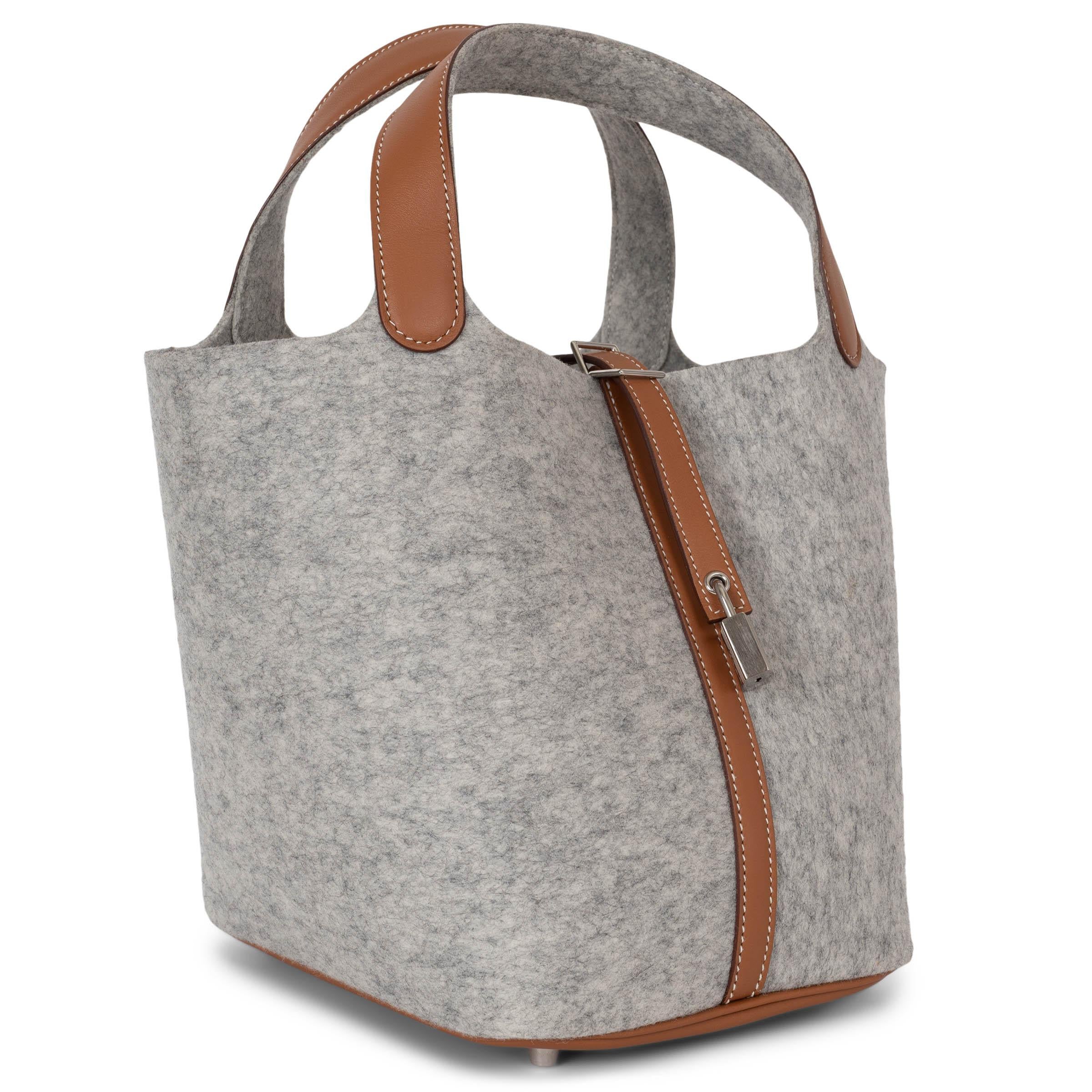This 100% authentic Hermès Picotin 22 bag in Gris Claire (light grey) wool felt exudes understated elegance. Featuring Gold (camel) Veau Swift leather trims with contrasting white stitching, it beautifully showcases Hermès' craftsmanship. The