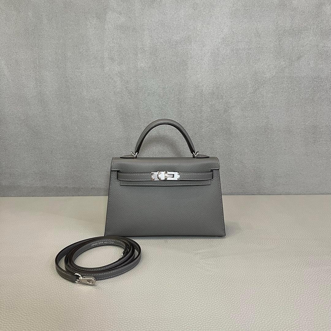 Jewell Aficionado propone la splendida Hermès Gris Meyer/Noir Mini Kelly 20 Verso in pelle Epsom, un pezzo davvero unico e molto ricercato. La combinazione di Gris Meyer e Noir, un sofisticato abbinamento di grigio chiaro e nero intenso, crea un