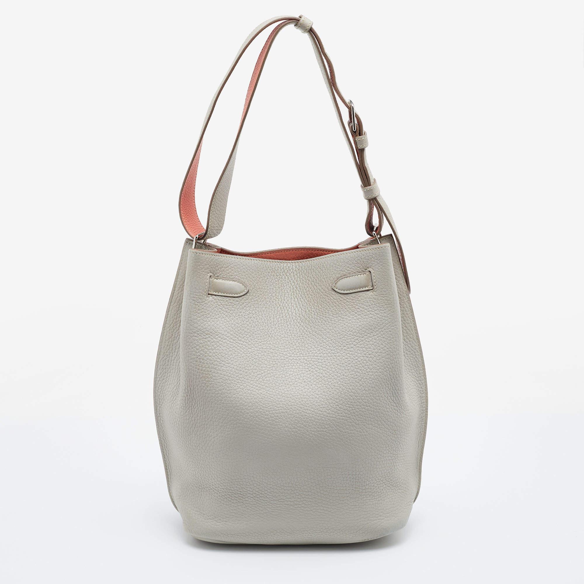 The elegant and timeless elements of the iconic Kelly are coupled with a more casual silhouette in this coveted So Kelly bag. It is crafted from Gris Perle/Crevette leather in a bucket-like shape with the signature Kelly lock in silver-tone metal on