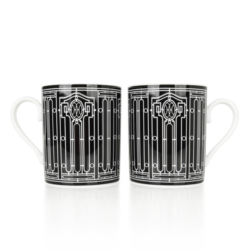 Garantiert authentisches Paar Hermes H Deco Tassen in Schwarz mit Weiß. 
Mit schmiedeeisernen Friesen im Art-déco-Stil. 
Jede 10-oz-Tasse ist aus Porzellan. 
Alle sind im Deco-Design gestaltet. 
Jede Tasse wird mit einer charakteristischen