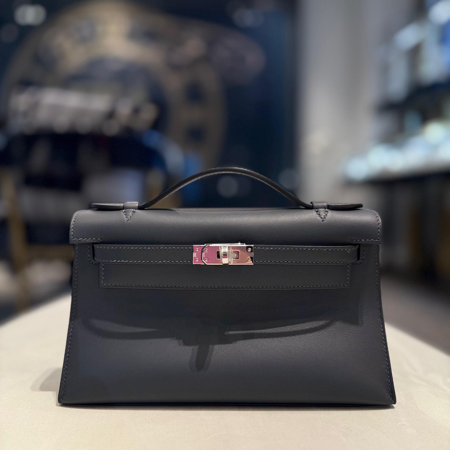 Jewell Aficionado propone una Pochette Hermès Gris Kelly in pelle Veau Swift, un pezzo raffinato e versatile in una fresca tonalità di grigio. Realizzata in pelle morbida ed elastica e rifinita con hardware in palladio, è elegante e leggera,