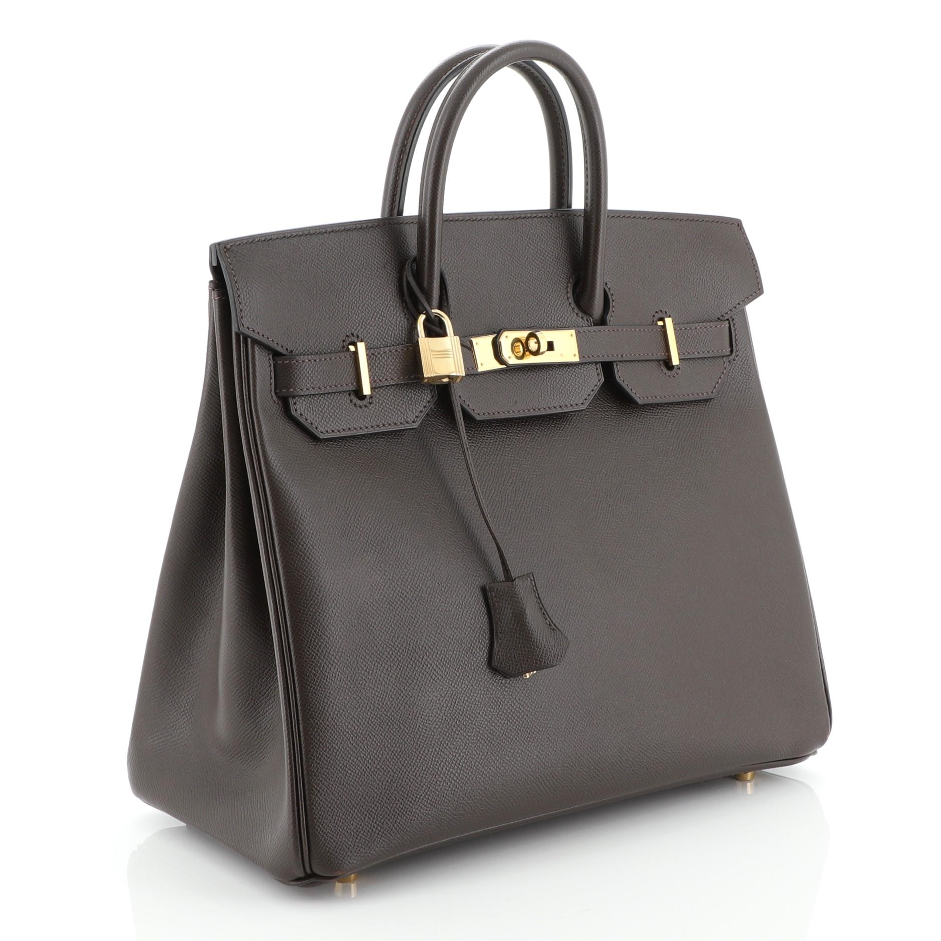 This Hermes HAC Birkin Bag Ebene Courchevel with Gold Hardware 32, crafted in Ebene brown Courchevel leather, features dual rolled handles, frontal flap, and gold hardware. Its turn-lock closure opens to an Ebene brown Chevre leather interior with