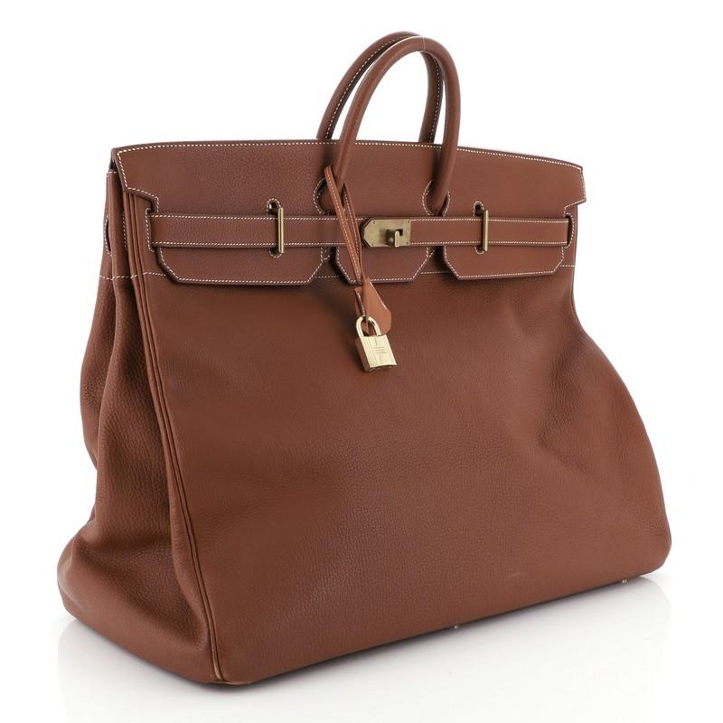 This Hermes HAC Birkin Bag Etrusque Fjord with Gold Hardware 55, crafted in Etrusque brown Fjord leather, features dual rolled handles, front flap, and gold hardware. Its turn-lock closure opens to an Etrusque brown Chevre leather interior with zip
