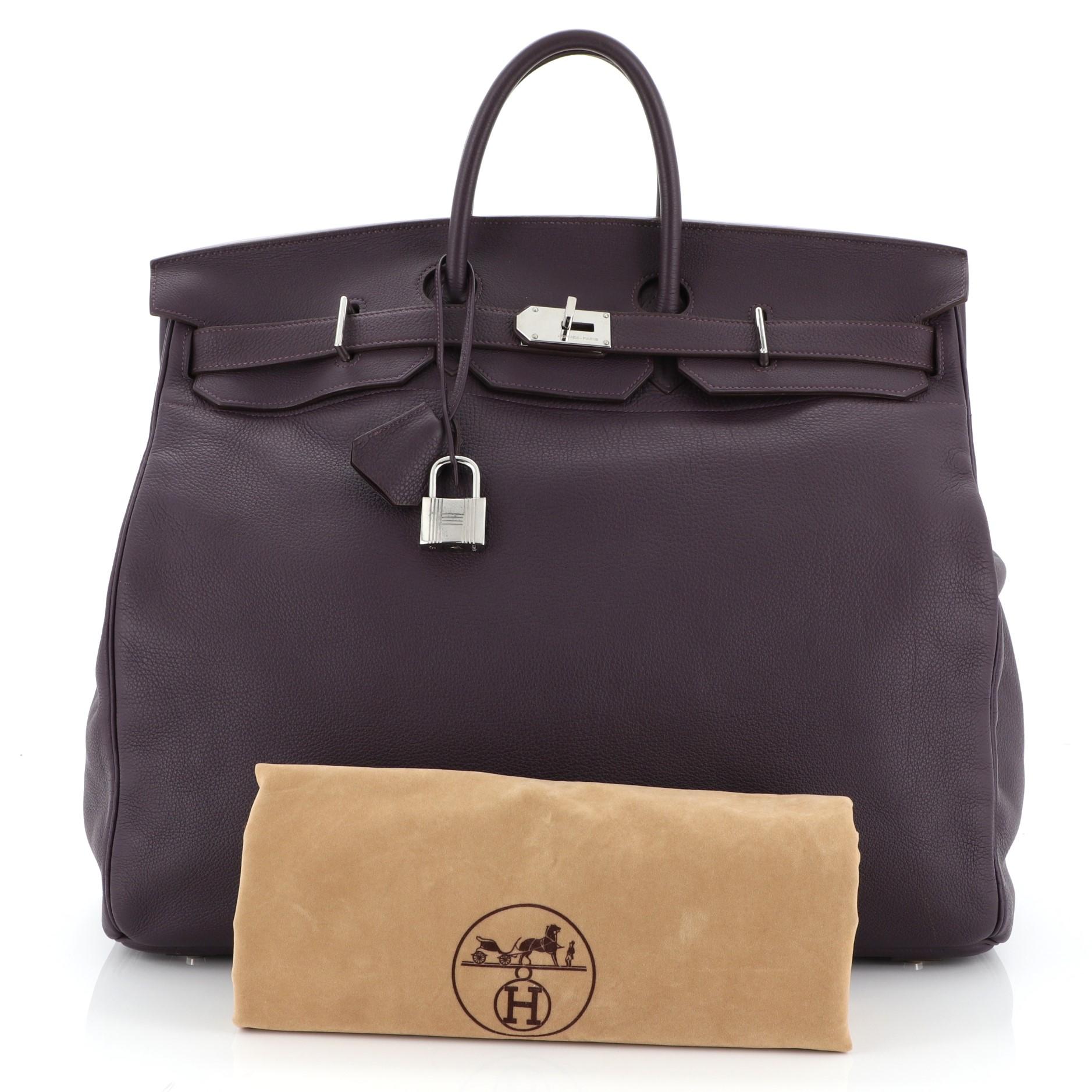 This Hermes HAC Birkin Bag Raisin Clemence with Palladium Hardware 50, crafted in Raisin purple Clemence leather, features dual rolled handles, front flap, and palladium hardware. Its turn-lock closure opens to a Raisin purple Clemence leather