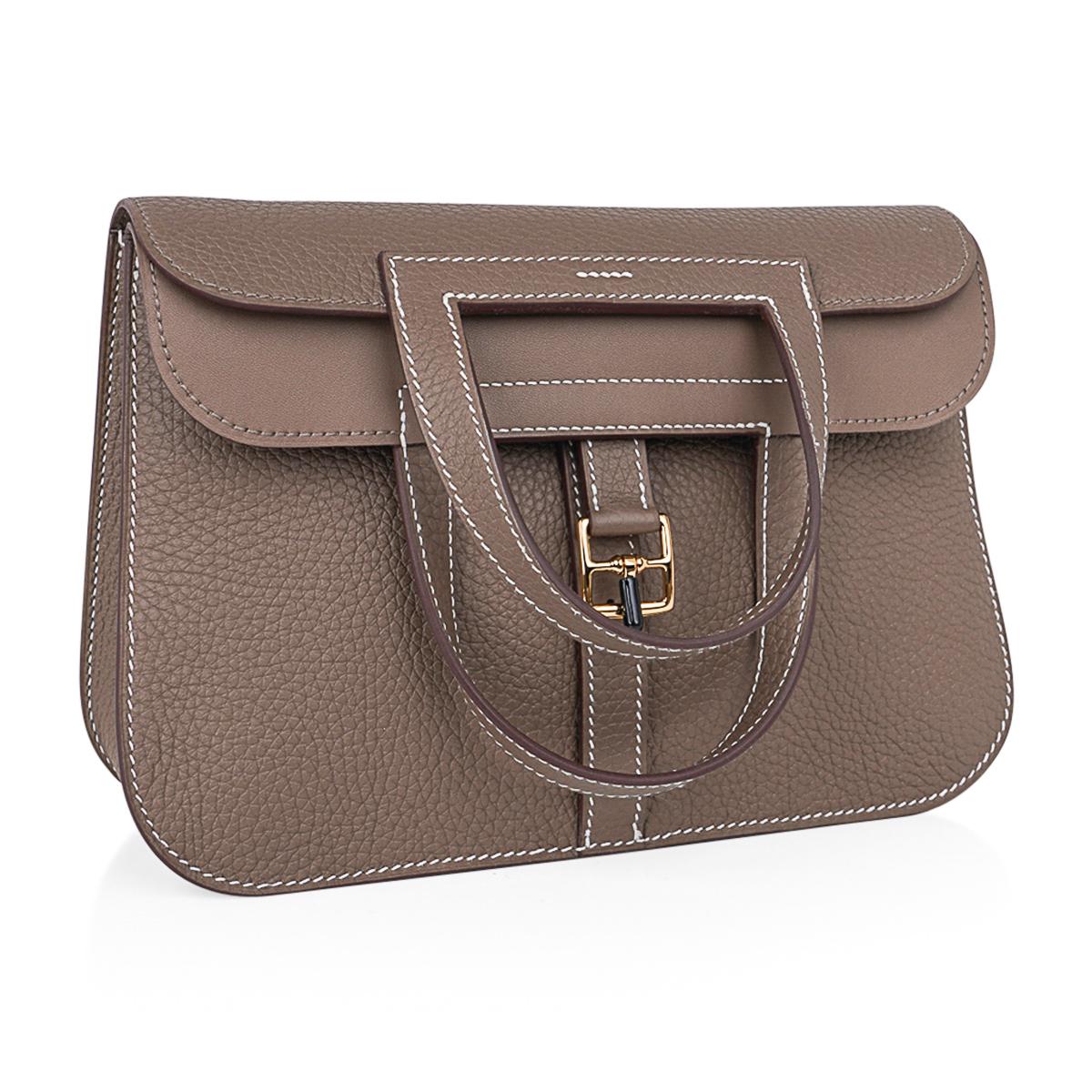 Mightychic offers an Hermes Halzan 25 bag featured in Etoupe Clemence leather.
Lush with Gold hardware.
Plush Clemence leather.
Versatile three-way bag.
The Hermes Halzan bag is a fresh take on the messenger with the crossbody strap.
Fold over with