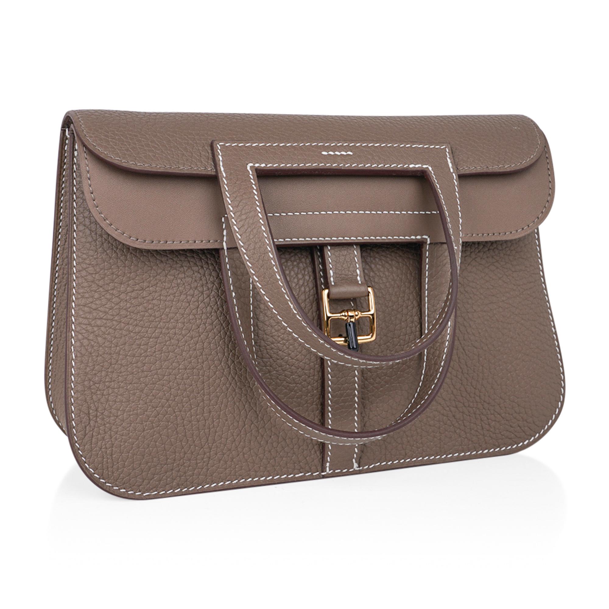 Guaranteed authentic Hermes Halzan 25 bag featured in Etoupe Clemence leather.
Lush with Gold hardware.
Plush Clemence leather.
Versatile three-way bag.
The Hermes Halzan bag is a fresh take on the messenger with the crossbody strap.
Fold over with