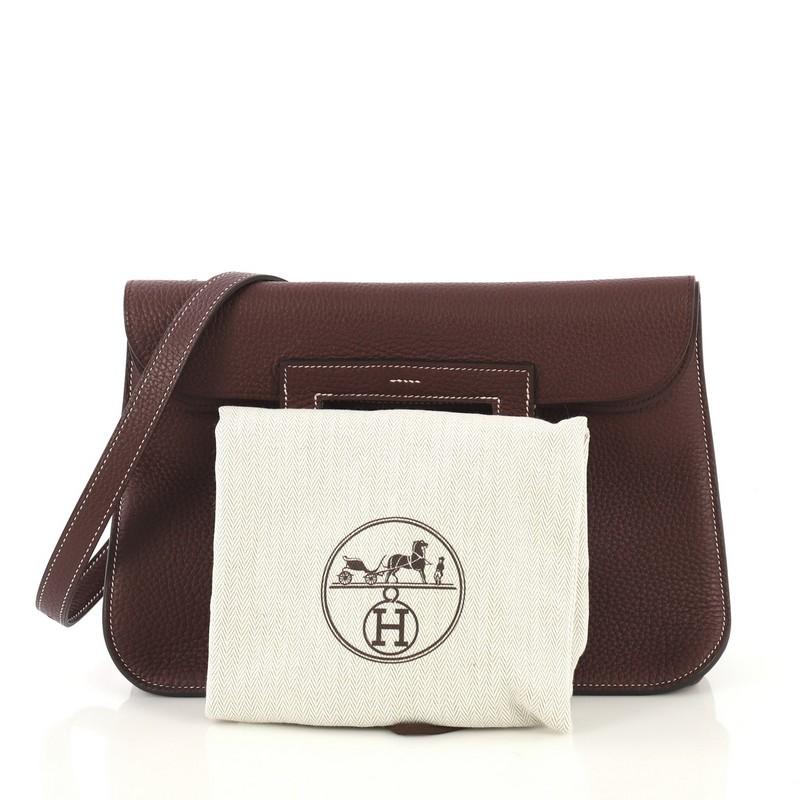 This Hermes Halzan Handbag Clemence 31, crafted from Bordeaux burgundy Clemence leather, features dual stirrup-shaped top handles, flat shoulder strap, four exterior flat pockets, and palladium hardware. Its buckle closure opens to a  Bordeaux