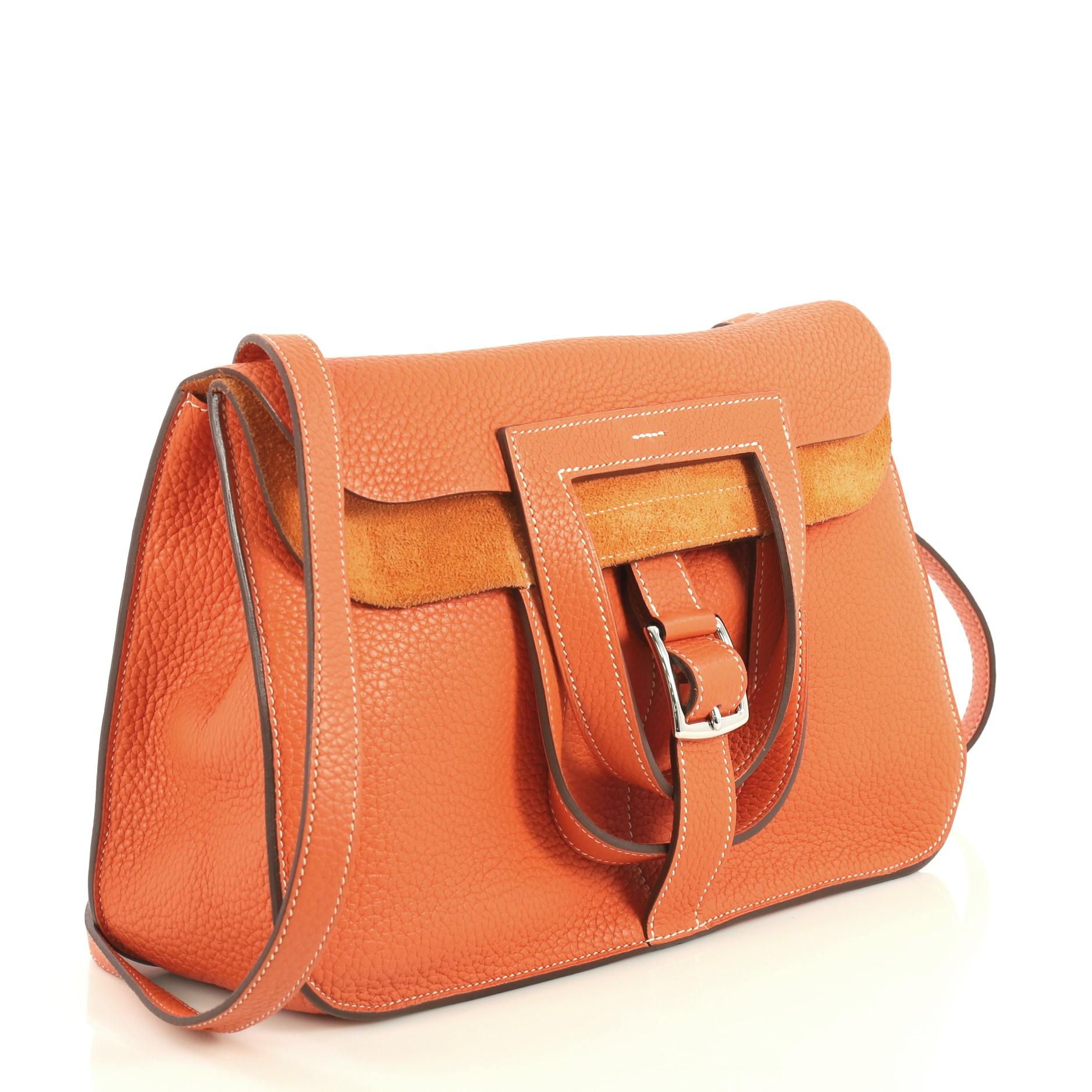 This Hermes Halzan Handbag Clemence 31, crafted from Orange Poppy orange Clemence leather, features dual stirrup-shaped top handles, flat shoulder strap, four exterior flat pockets, and palladium hardware. Its buckle closure opens to an Orange Poppy