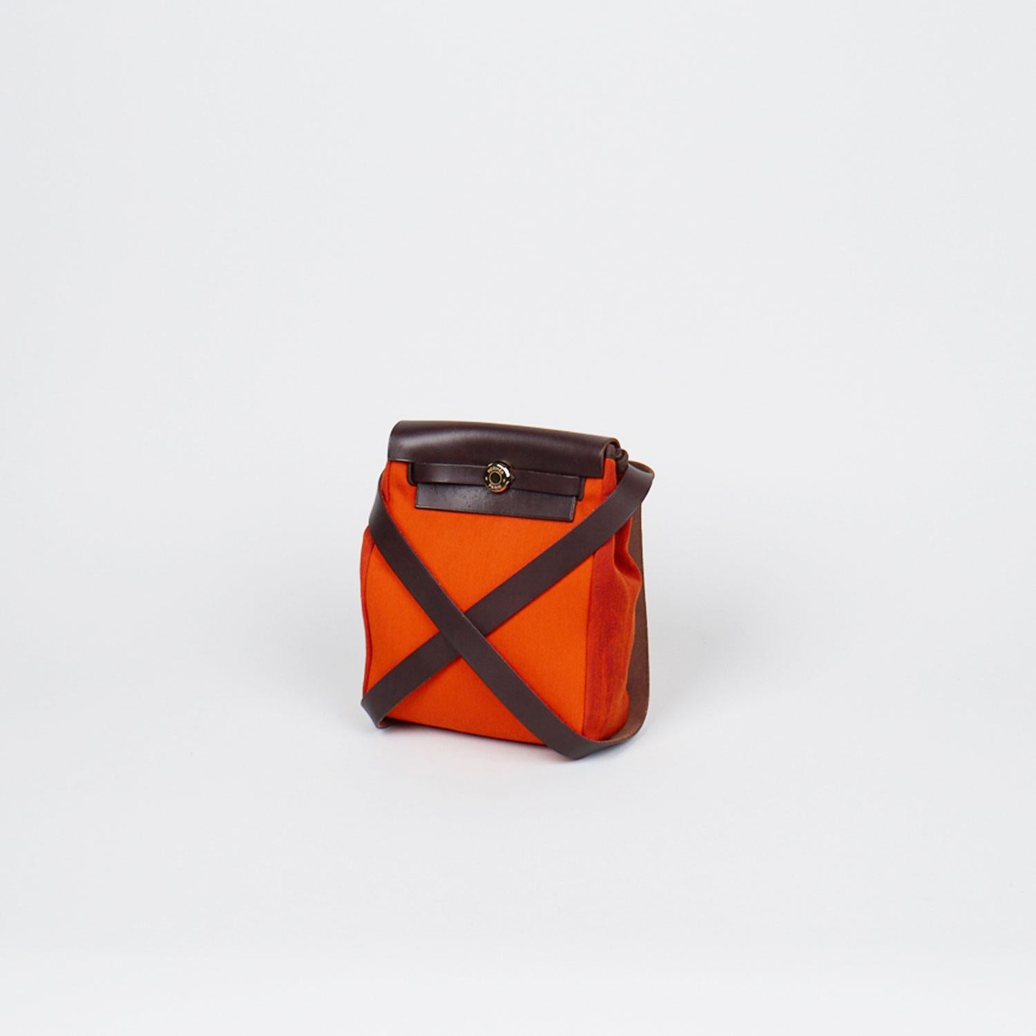 Orange Toile Hermès Herbag TPM with

- Silver-tone hardware
- Single flat shoulder strap
- Walnut Vache Hunter leather trim
- Dual interior compartments, tonal toile lining and pull-through closures at front flap

Overall Preloved Condition: Very