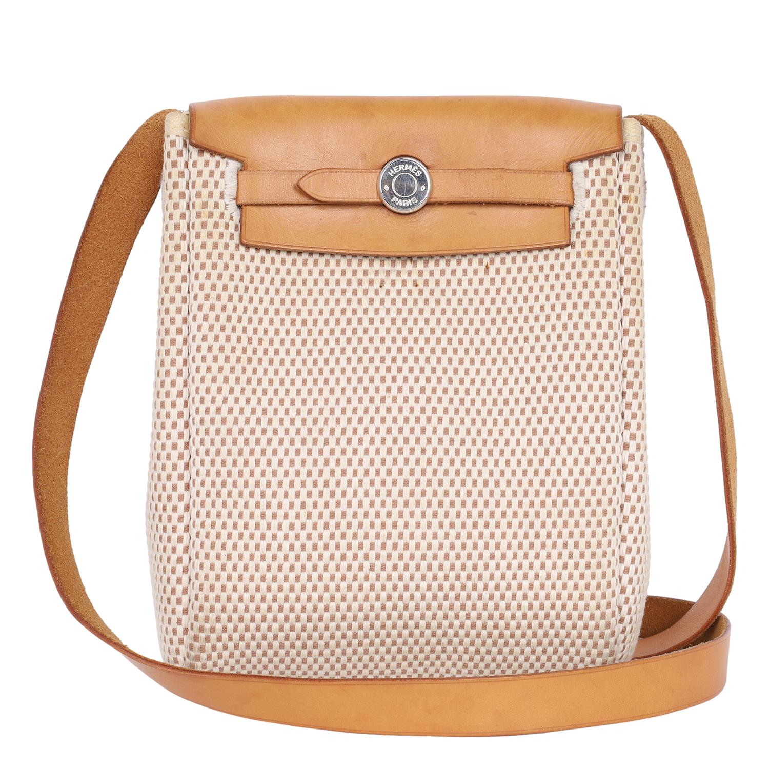 Authentic pre-loved Hermes Herbag TPM mini crossbody bag in beige and black.

Features beige and also a black toile canvas, changeable leather top with a flap, silver hardware, long leather shoulder strap. This unique bag can be used as beige or