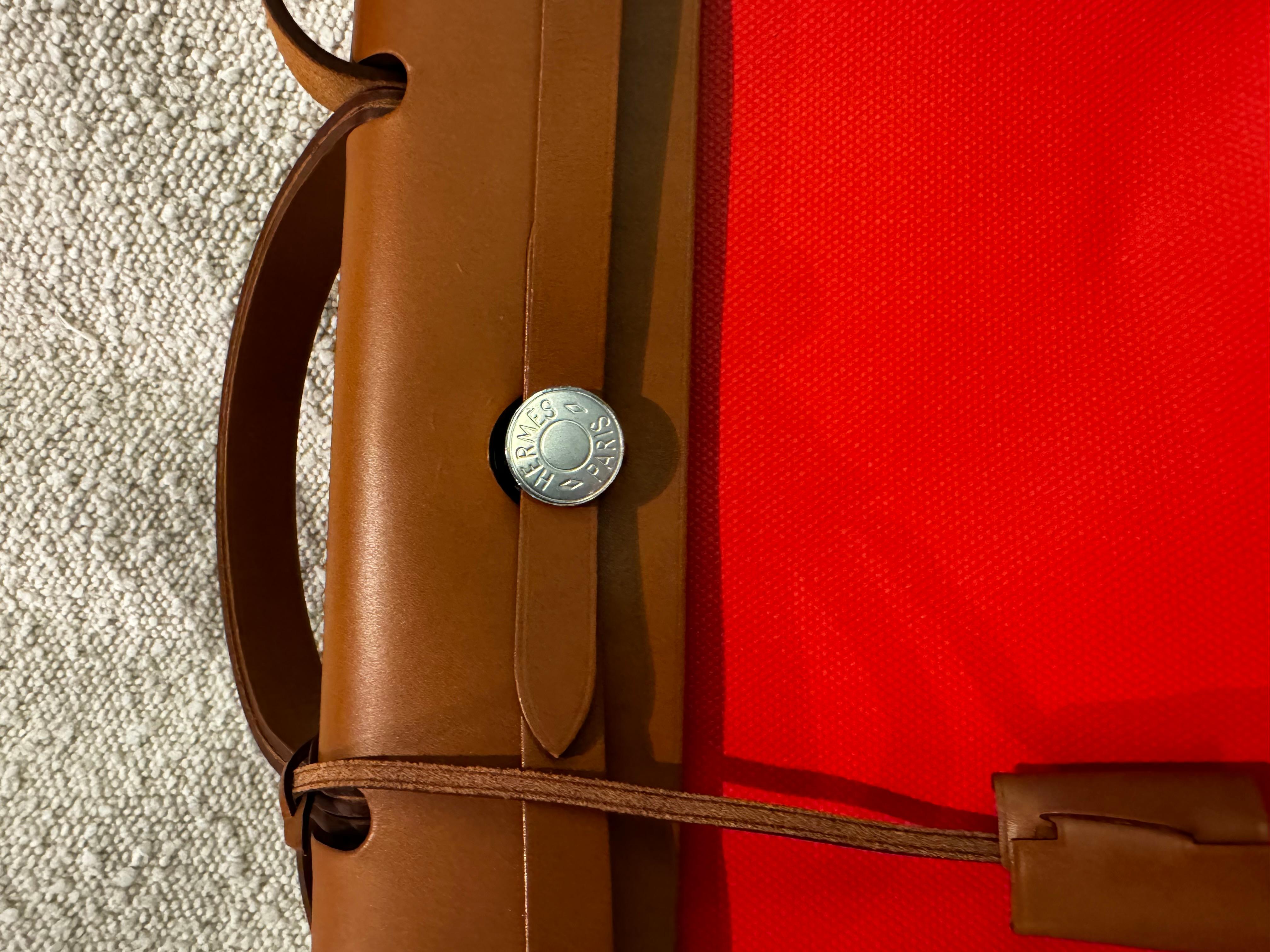 Hermès Herbag Zip 31  Fauve Vache and Orange Mecano Toile PM Palladium Hardware. Hermès Herbag 31 is handcrafted from Vache Hunter in Fauve and finished with the signature “Clou de Selle” clasp. The body is made from Orange Mécano and Écru Coated