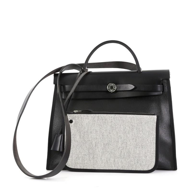 This Hermes Herbag Zip Leather and Berline Vache Canvas 31, crafted in Noir black Vache Hunter, Toile H and Toile Berline, features a leather top handle, external zip pocket, and palladium hardware. Its frontal rod opens to a gray Toile H interior.