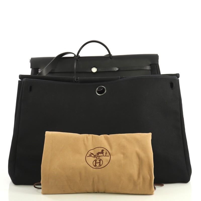 This Hermes Herbag Zip Leather and Toile 50, crafted in Noir black Toile Officier and Vache Hunter leather, features a top leather handle, external zip pocket and brushed palladium hardware. Its frontal rod opens to a Noir black Toile Officier
