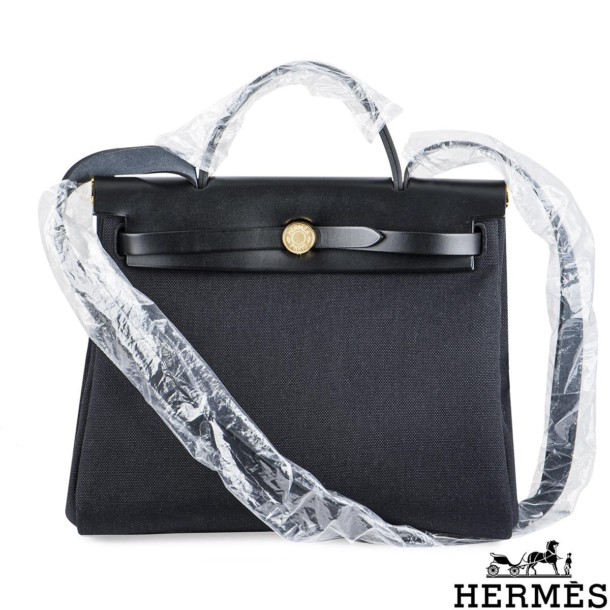 A chic Hermes Herbag Zip 31 handbag. The exterior of this Herbag features a top handle with a crossbody strap in Noir Vache Hunter leather on the top section whereas the body of the bag is made out of Noir Toile Militaire canvas, has a Clou de Selle