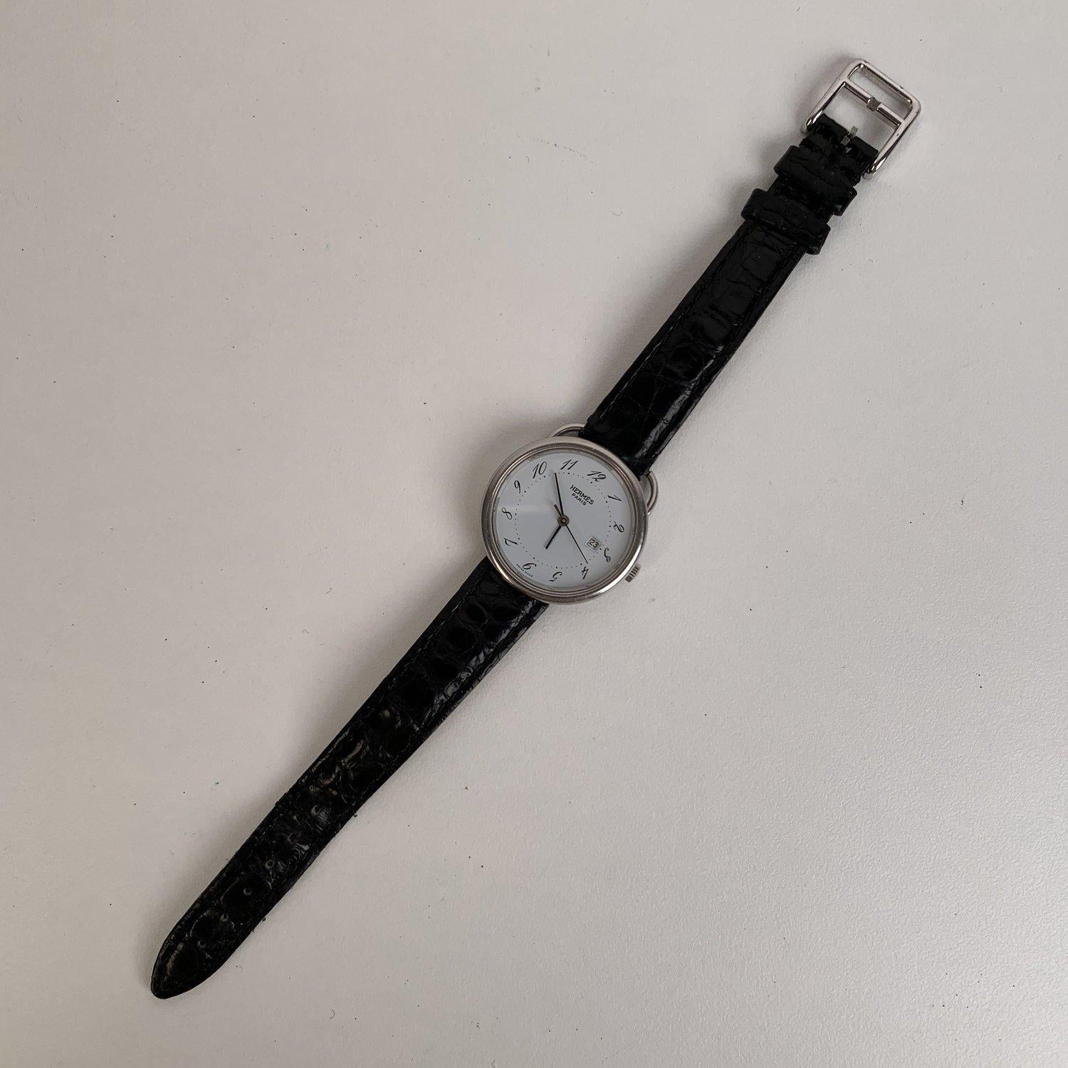 Description Timeless Hermes Vintage 'Arceau' silver-tone wrist watch with quartz movement. Swiss Made. Round stainless steel case. White dial with Arabic script numeral hour markers. Date at 3 o'clock. Sapphire crystal. Black crocodile leather wrist