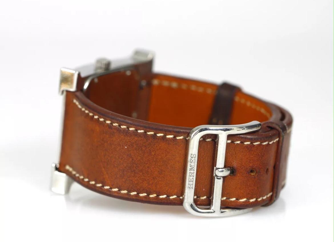 Up for sale is a timeless classic, an HERMÈS Heure H wristwatch. A stunning piece of jewelry and an elegant timepiece for women. The stainless steel case and silver bezel give it a classic and sophisticated look, while the white dial and brown
