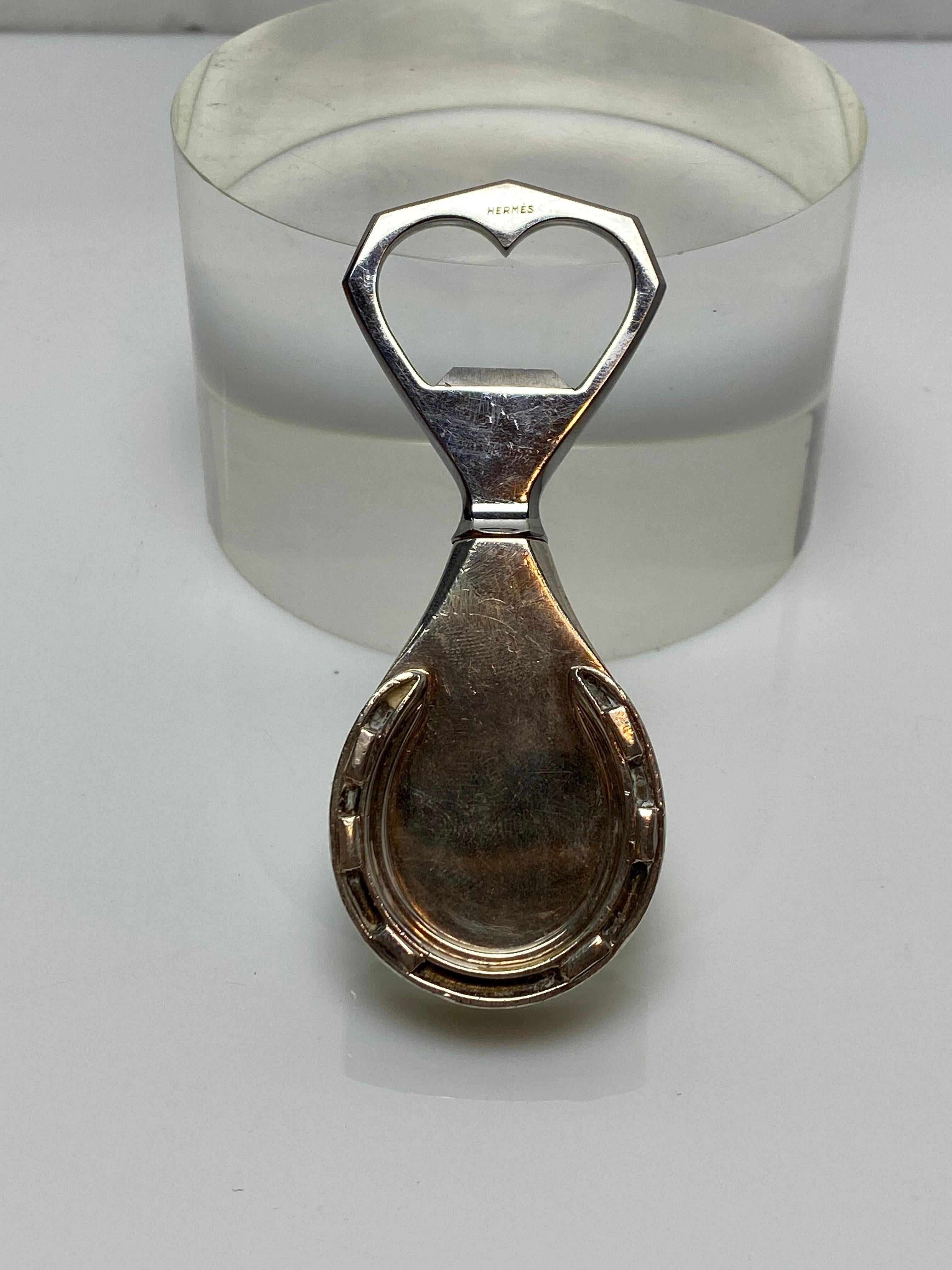An elegant bottle opener by Hermes. The handle is formed in a tear drop shape with a figural horseshoe applied.

Made for Hermes by Ravinet D'enfert.