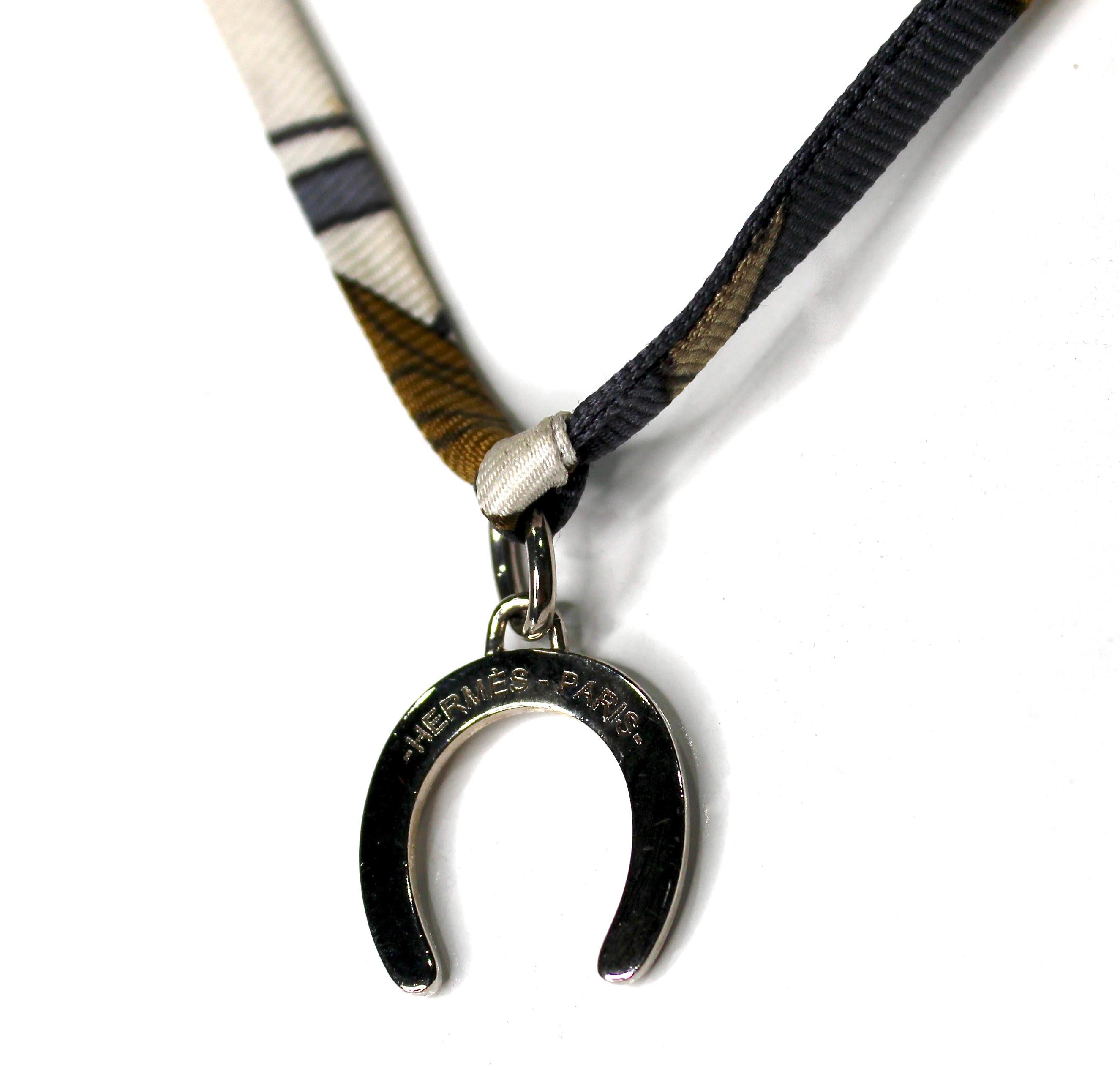 El Collar de Corbata con Colgante Hermes Herradura es un accesorio chic y versátil que combina elegancia con un toque de capricho. Confeccionado con un fino cordón de tela con un elegante estampado, ofrece un ajuste ligero y cómodo para llevarlo a