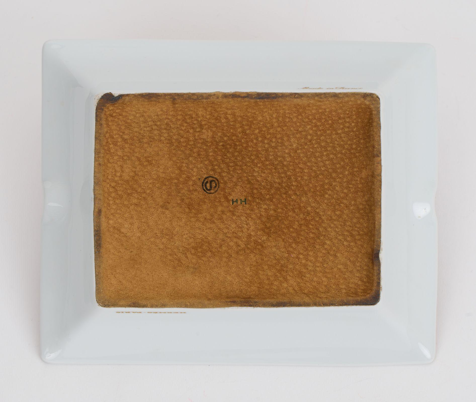 Dieser Hermès-Aschenbecher mit zwei Hunden vor einer Backsteinmauer auf weißem Hintergrund mit rostrotem Rand und goldfarbener Umrandung.  Dieser Aschenbecher ist eine perfekte Ergänzung für jeden Schreibtisch oder Couchtisch. Geringe Abnutzung auf